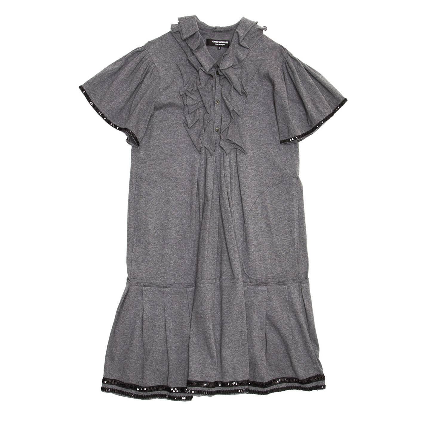Grey cotton jersey dress with raw edge frills to decorate the collar and bib detail. The skirt part is pleated with a 70's style and the bottom is decorated with two black sequined ribbons. The sleeves are short, gathered at top shoulder and