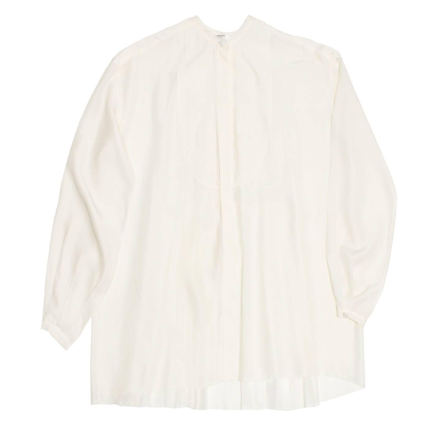 Beautiful ivory silk shirt with round collar and bib front designed by a subtle tone-on-tone line of stitching. The front is closed from bust to hem with only one self-fabric covered button at neck. The back panel is fully pleated from yoke to hem,