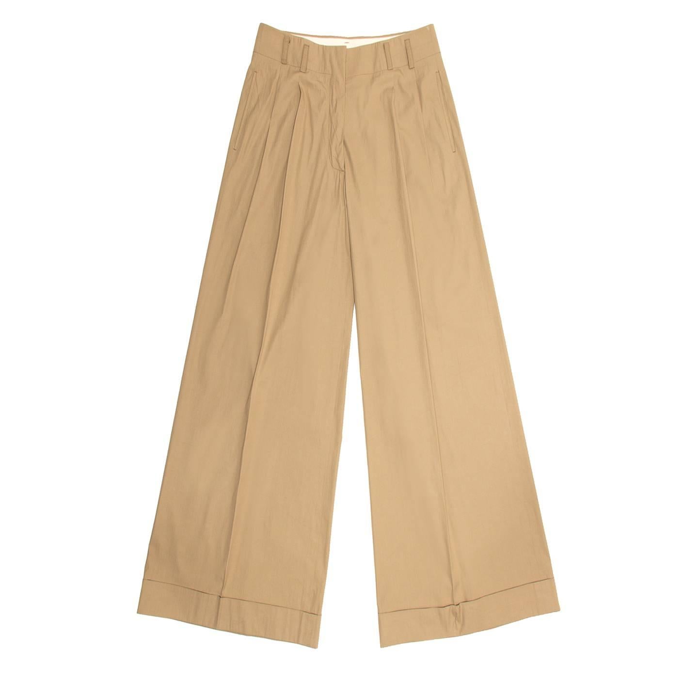 Khaki light cotton blend palazzo trousers with very wide legs and turn-ups at hem. The pants are pleated, the front is flat and a hidden hook fastens the waist band, which is enriched by small belt loops. Slash pockets sit at front side seams, while