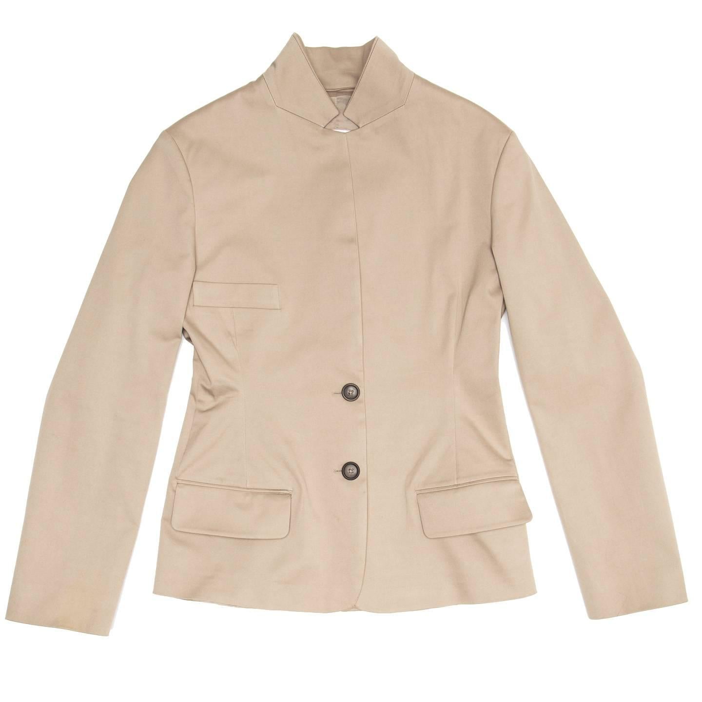 Taupe single breasted cotton jacket that fastens with 2 dark buttons at waist leaving a long lapel. The shape is fitted, the front enriched by a classic breast pockets and two flap pockets at hips, while the back has a long shapes vent that starts