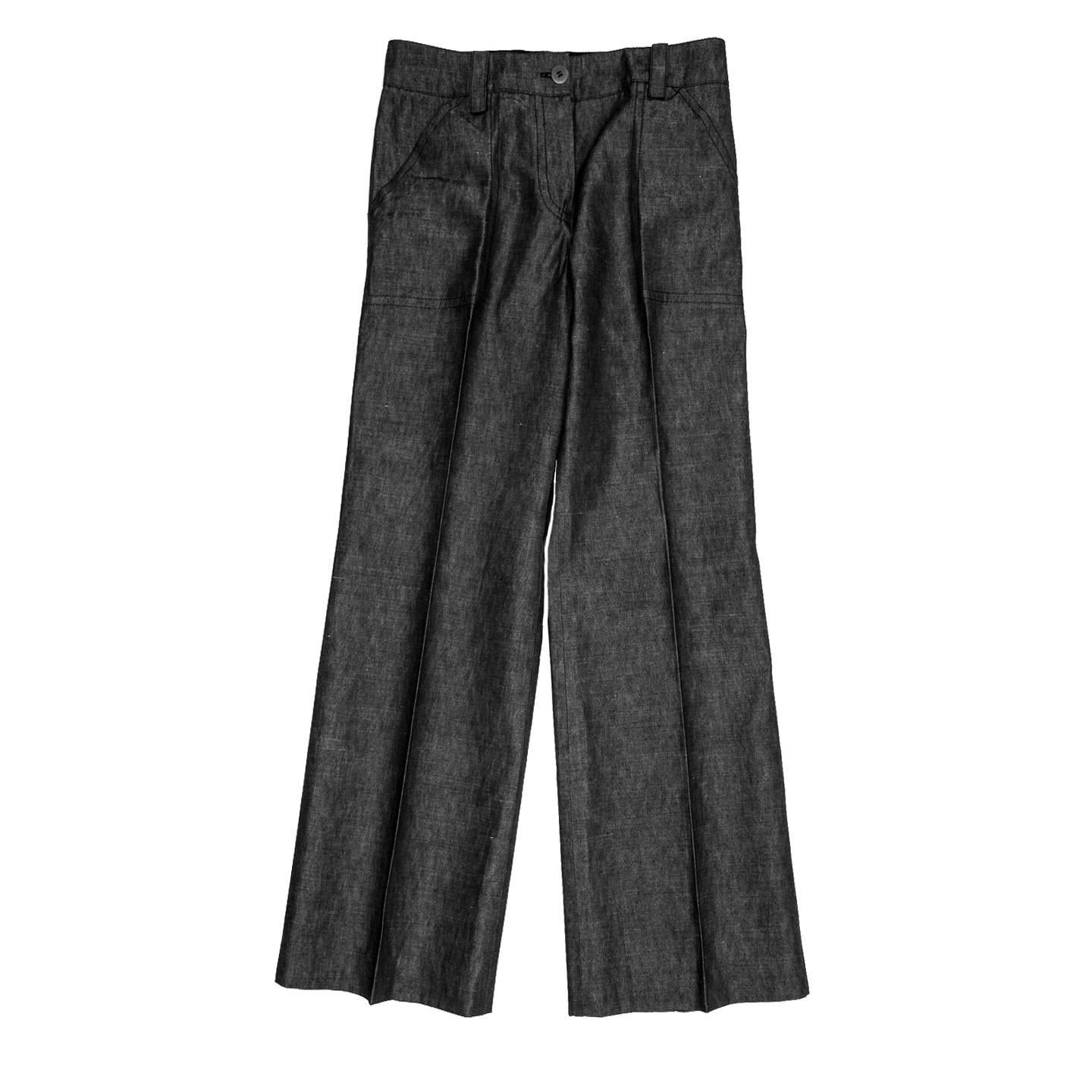 Cotton & ramie blend denim trousers palazzo style suit pleated. The front pockets are slanted, at back the slit pockets fasten with a metal button and loop and their shapes are delineated by double rows of dark blue top stitches to match the ones on