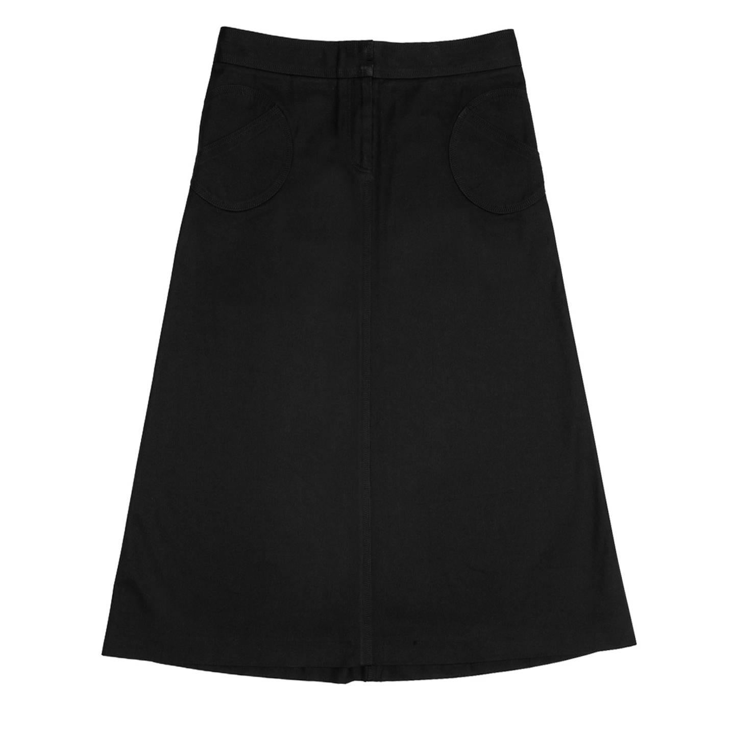 Black thick cotton skirt with an up side down back yoke that extends creating side seams on the back panels leaving space in the front sides for beautiful round patch pockets. The fit is A-shape with high waist and below knee length. All the seams