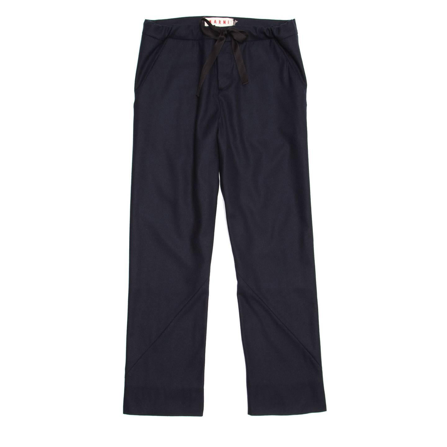 Navy virgin wool blend light flanel trousers with a straight leg fit. Front and back are flat, a ribbon drawstring makes the waist adjustable and enriches the front, while a seam detail follows the slash pockets line and turns around the legs.

Size