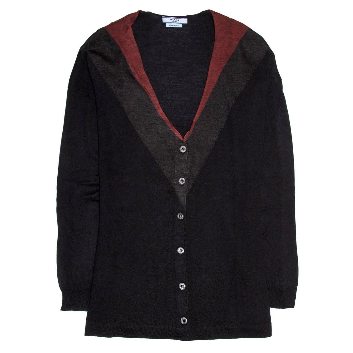 Prada Midnight blue wool and silk blend fine knit cardigan with red & charcoal grey knit inserts at V-neck and pleating detail at back. The fit is oversized, straight and lower hip length. 

Size  44 Italian sizing 

Condition  Good: never worn