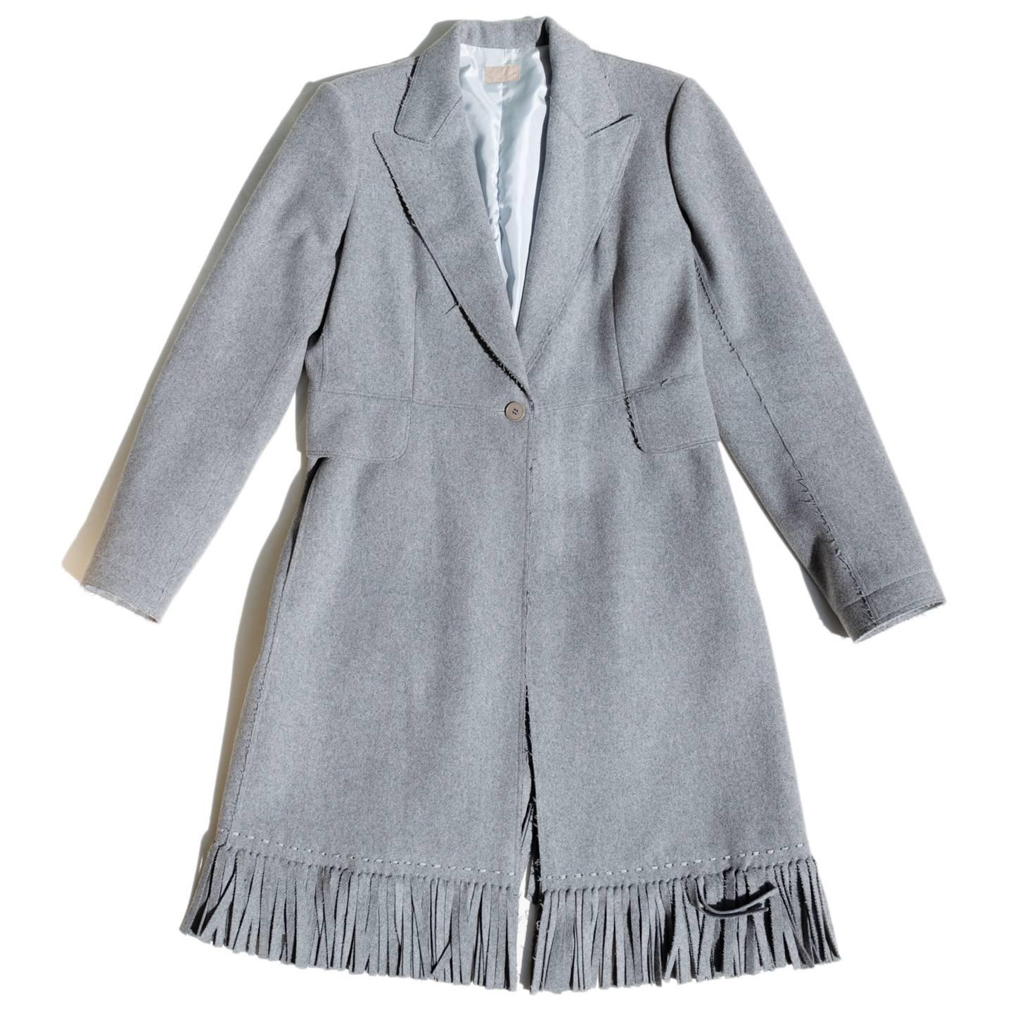 Grey Alaïa wool & cashmere blend coat featuring fringe trim throughout, peaked lapels, dual flap pockets at sides and single button closure at front.

Size  44 French sizing

Condition  Excellent: Never Worn
