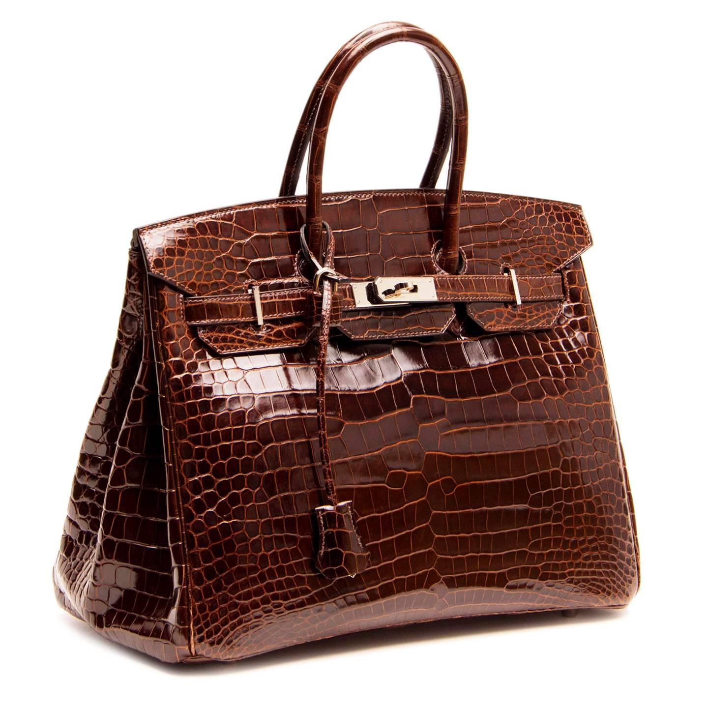 Beautiful chocolate brown crocodile Birkin 35cm bag with rolled handles and front flap that fastens with palladium turn-clasp buckle closure. This exquisite Chocolate Brown Porosus Crocodile Birkin is very rare to find in the shiny finish. Porosus,