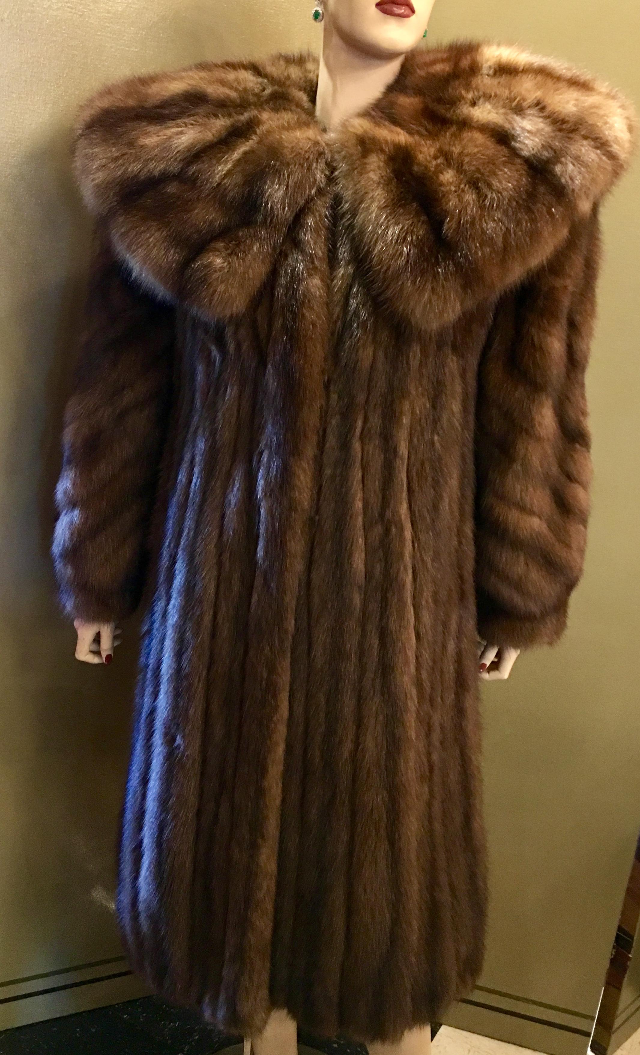 Very lavish and regal genuine natural Royal Crown Russian Sable fur coat features a large and very high fashion wide shawl style collar. The coat is lined in a silky dark brown fabric. Coat has velvet lined pockets and closes with hooks and eyes.