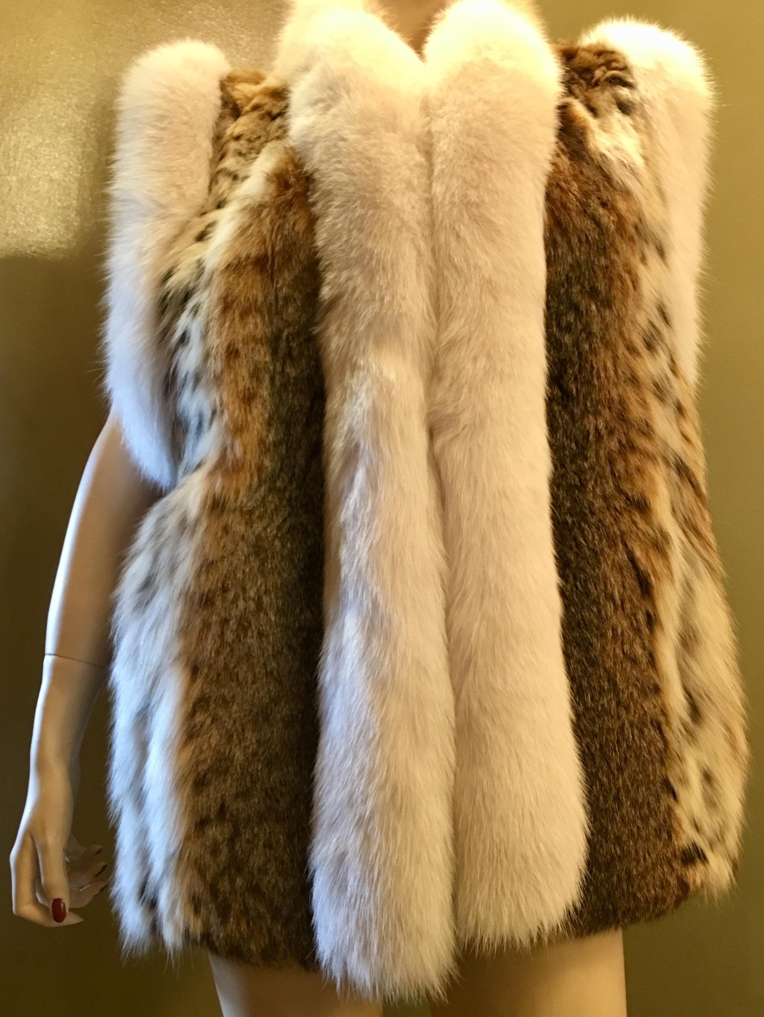 Strikingly marked lynx fur vest with vivid coloration, contrasts with white fox fur trim around the arm openings and the front edges.  The pelts are very soft and silky to the touch.  Features velvet-lined slash pockets and a satiny, taupe colored