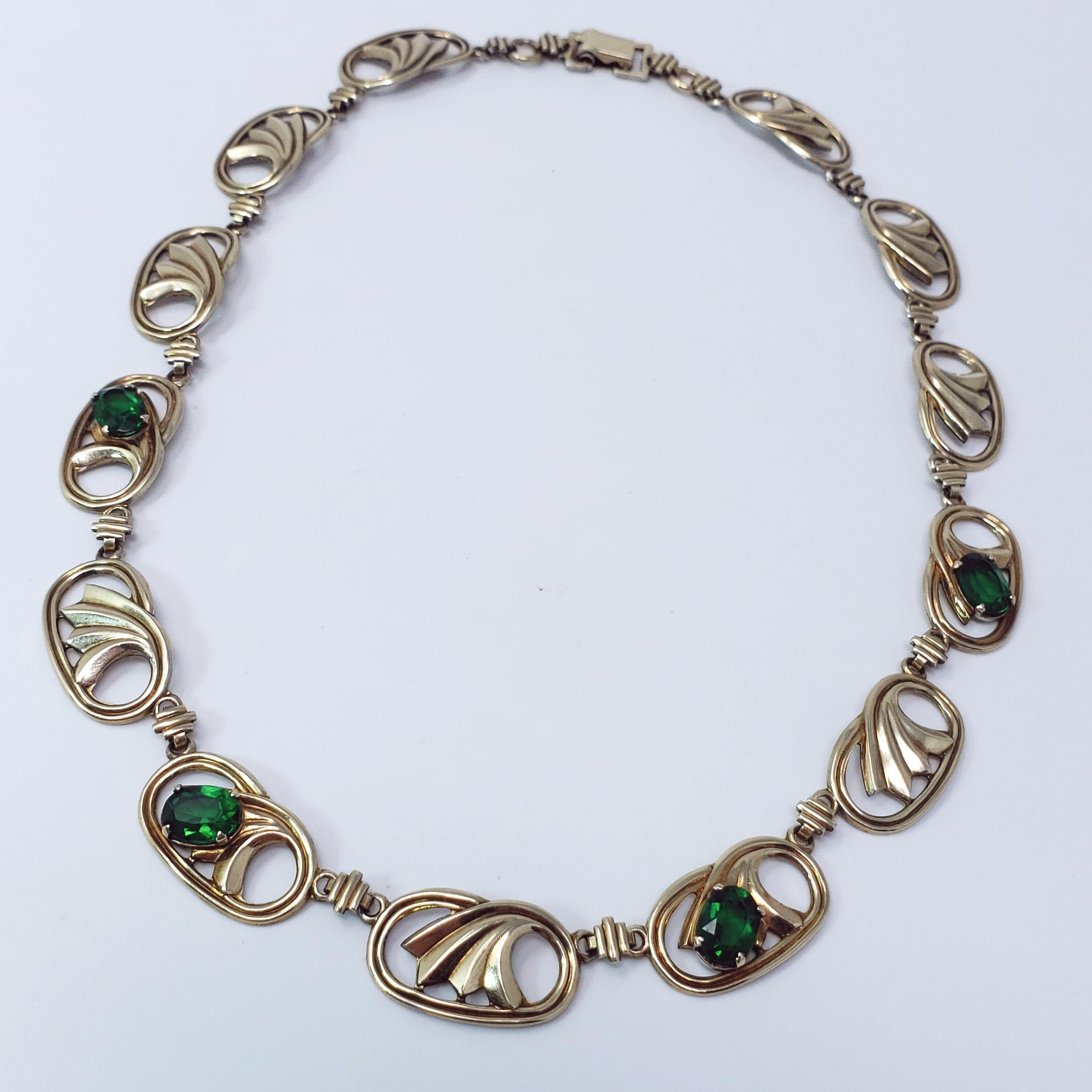 A vintage choker by Symmetalic. 14K gold plating on the front, sterling silver base links accented with green, emerald-colored faceted crystals in prong settings. A luxurious look. Made in the USA circa mid 1900s, with clear Edwardian
