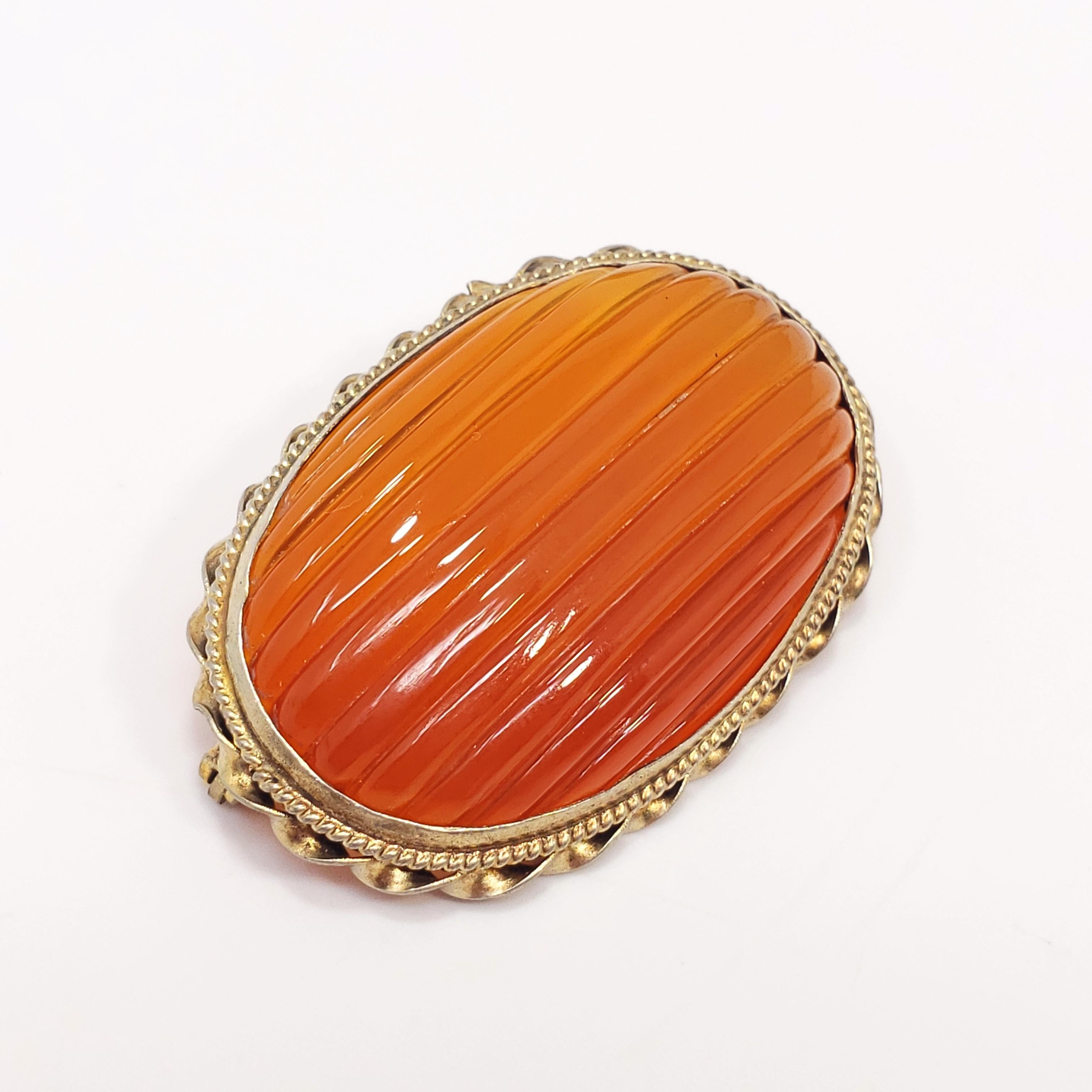 A carved carnelian gemstone in an ornate, Victorian, open-back, gilt brass, bezel setting. Antique spring ring clasp. The gemstone in this pin/brooch is beautifully carved and polished. A classic style!
