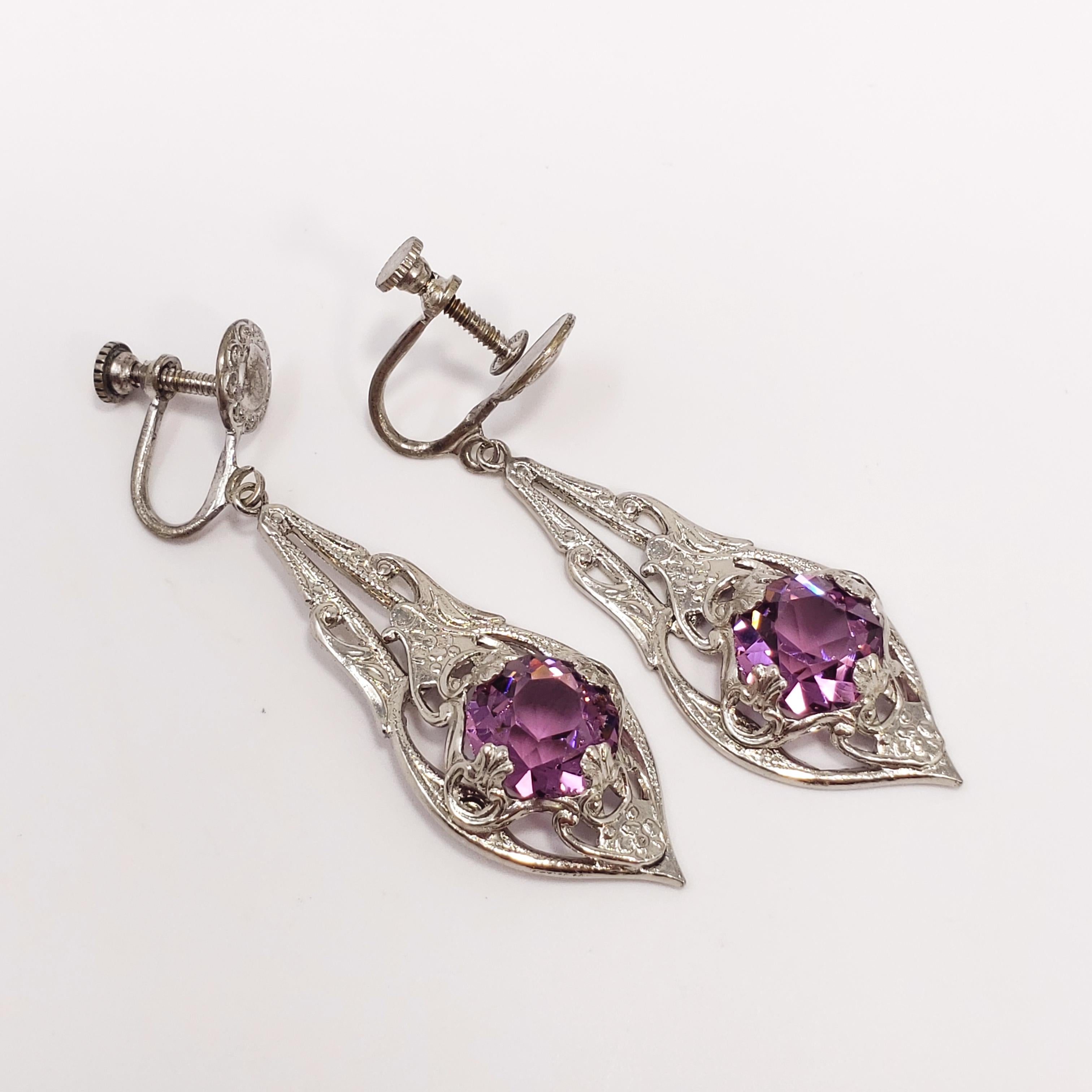 A pair of exquisite, antique, dangle earrings. The faceted, amethyst-colored crystals are prong set in an ornate, art-nouveau, silverplated metal setting. Feature antique screw back hardware. The expertly-cut crystals and .800 silver plating give