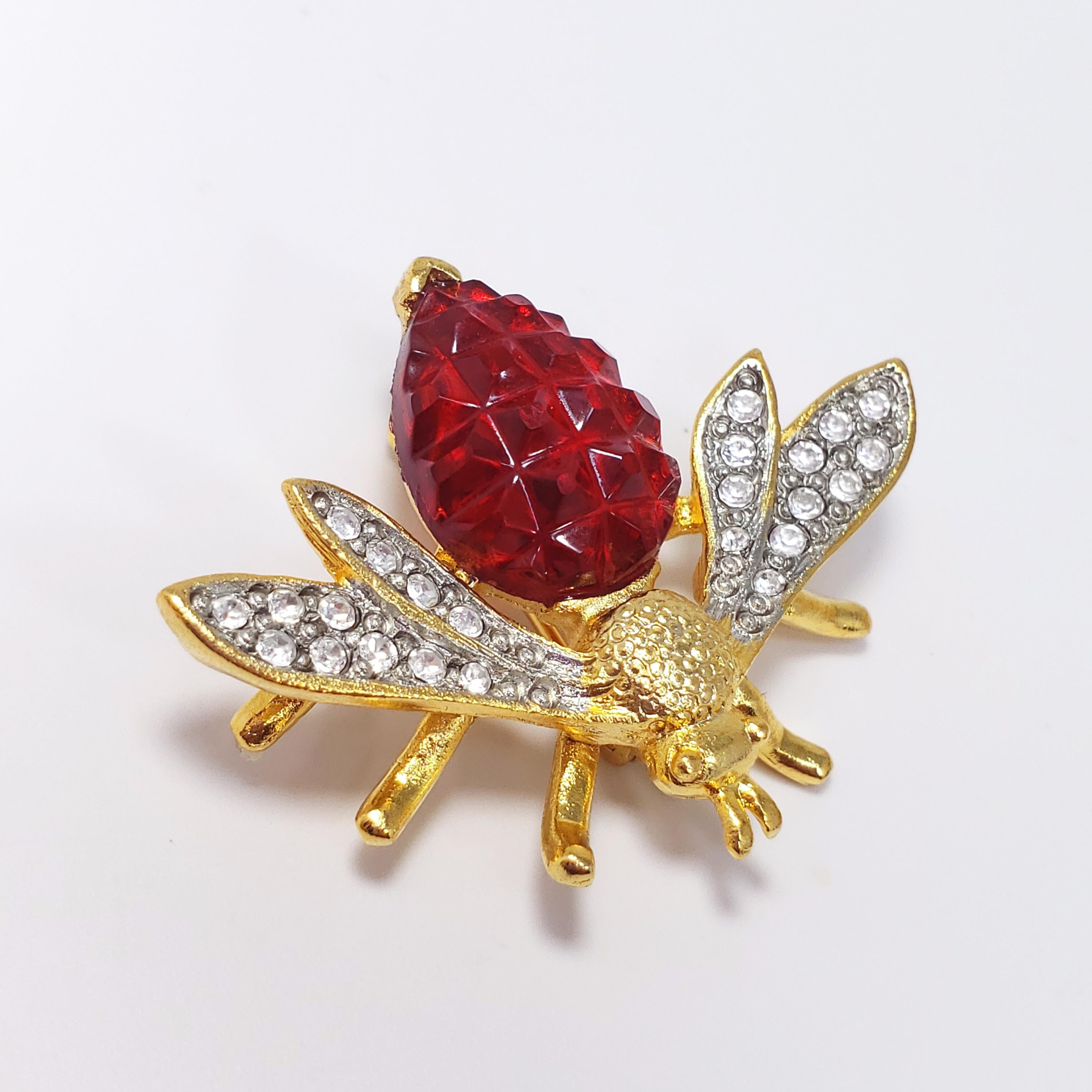 A colorful pin/brooch by Kenneth Jay Lane, the expert in costume jewelry! A fly/wasp/insect with clear crystal covered wings and a ruby-colored carved crystal abdomen, set in gold tone. Excellent for a formal occasion, or as a quirky