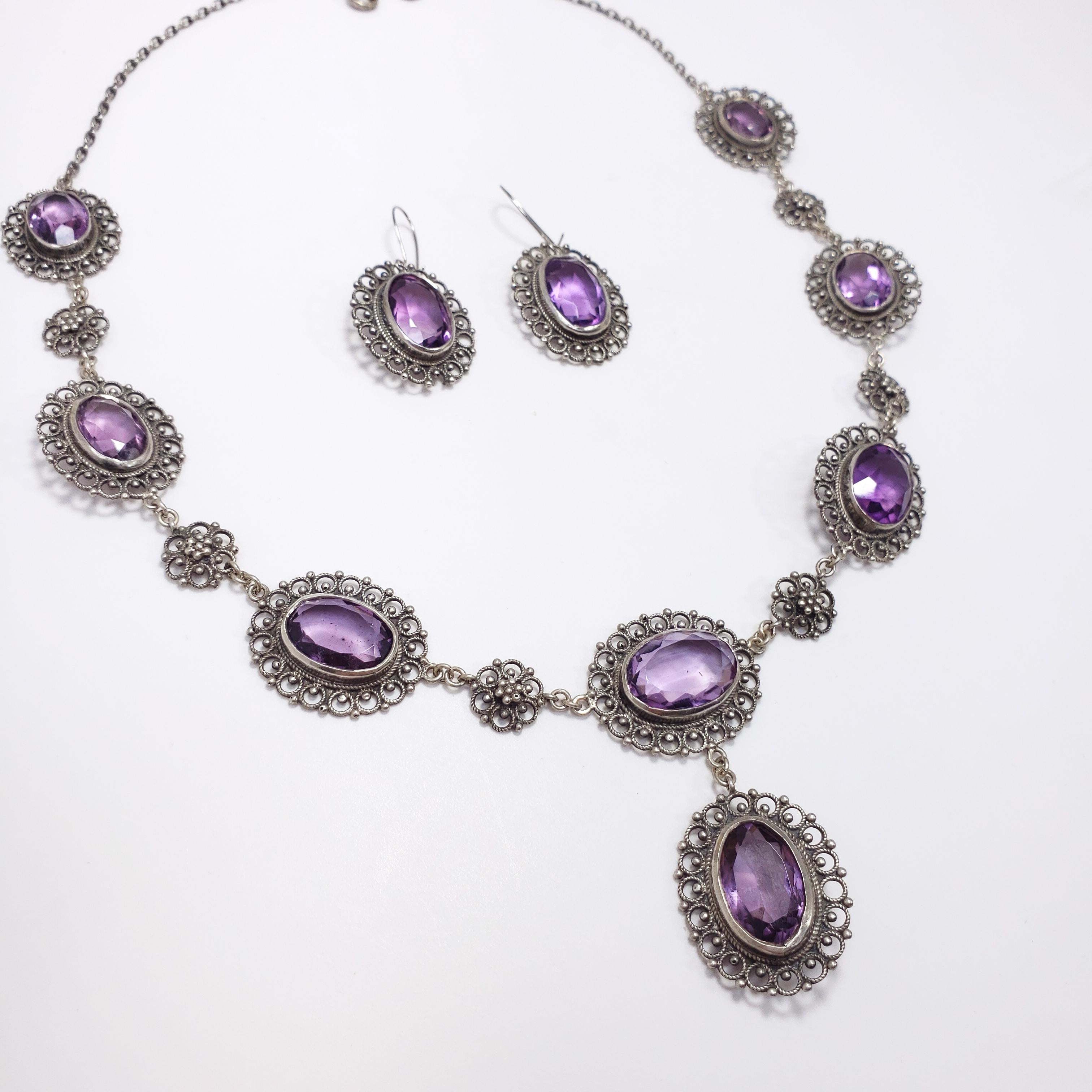 An absolutely regal demi-parure from the Victorian era, circa late 1800s. Features a drop necklace and pair of earrings in hallmarked 800 silver, with 8 graduated genuine amethysts in the necklace and a single amethyst in each earring, all in open
