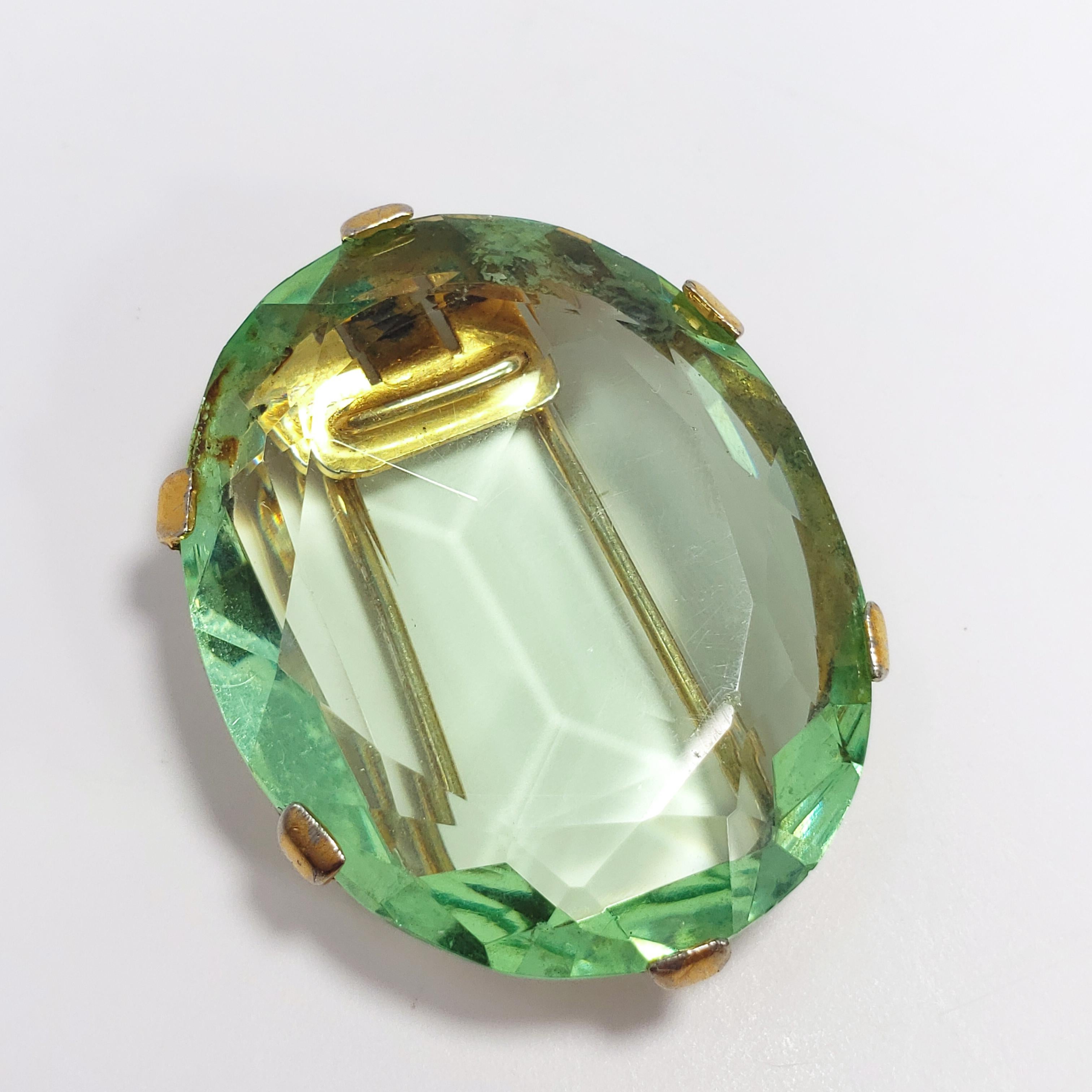 A Trifari Crown fur/dress clip designed by Alfred Phillipe during his time at Trifari. Features a large pale-emerald green colored crystal set in an open back, dual prong, clip bezel.

