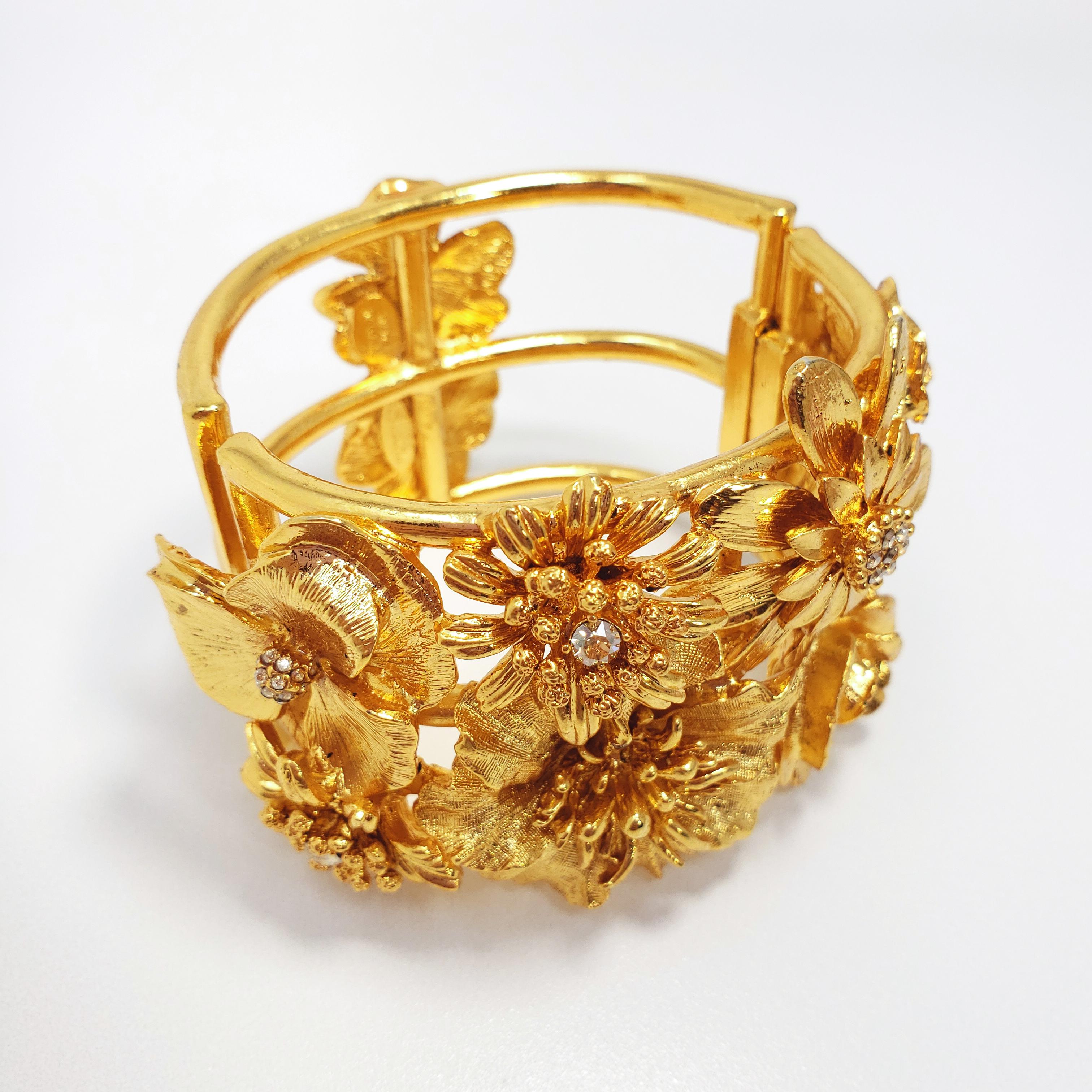 Bold and bright floral bracelet - features an assortment of blooming golden flowers accented with clear crystals. In the traditional bold Oscar de la Renta style!

Hallmarks: Oscar de la Renta, Made in USA
Dimensions: Inner circumference approx 6.5