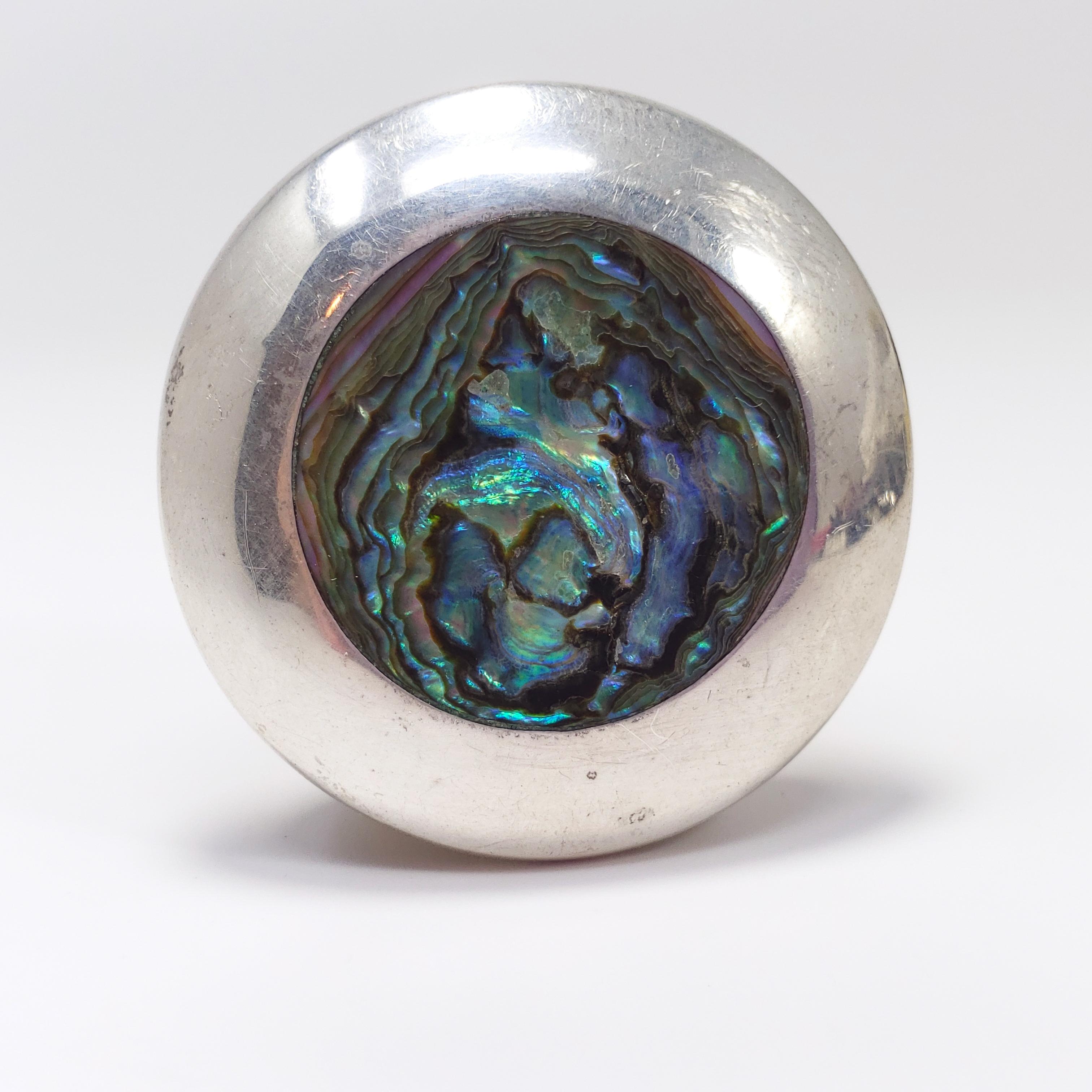 This accessory features an abalone shell inlay in a round sterling silver setting. Excellent Mexican silver craftsmanship. Can be used as either a necklace pendant or a pin/brooch.

Hallmarks: SFC, Mexico, 925
Weight: 8 g
Dimensions: L 3.8 x W 3.8 cm