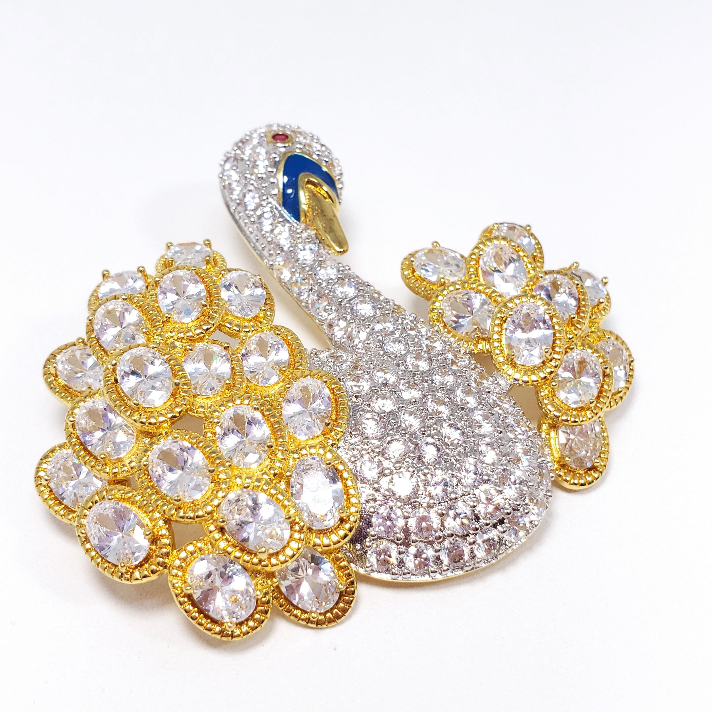 An ornate swan decorated with pave cubic zirconia and blue enamel, prong set in a gold plated metal. Brilliant luster and shine - this brooch is sure to catch everyone's attention! By Kenneth Jay Lane.

Hallmarks: © KJLane
