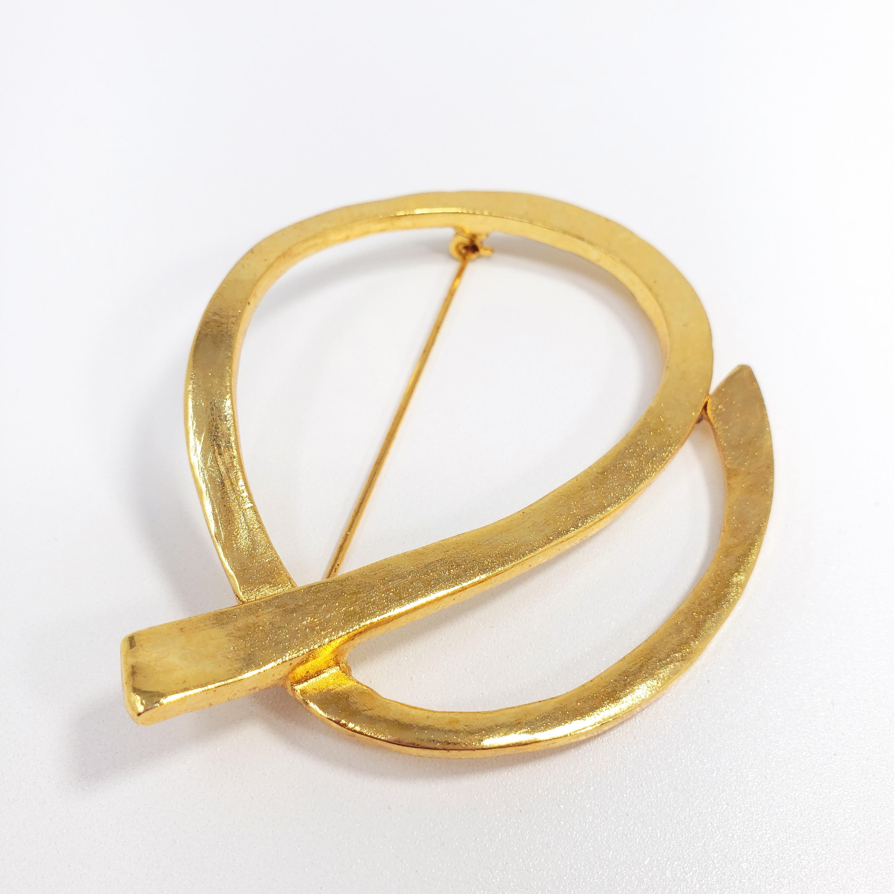 An abstract circular ribbon brooch/pin by Oscar de la Renta. Smooth gold finish.

Hallmarks: Oscar de la Renta, Made in USA