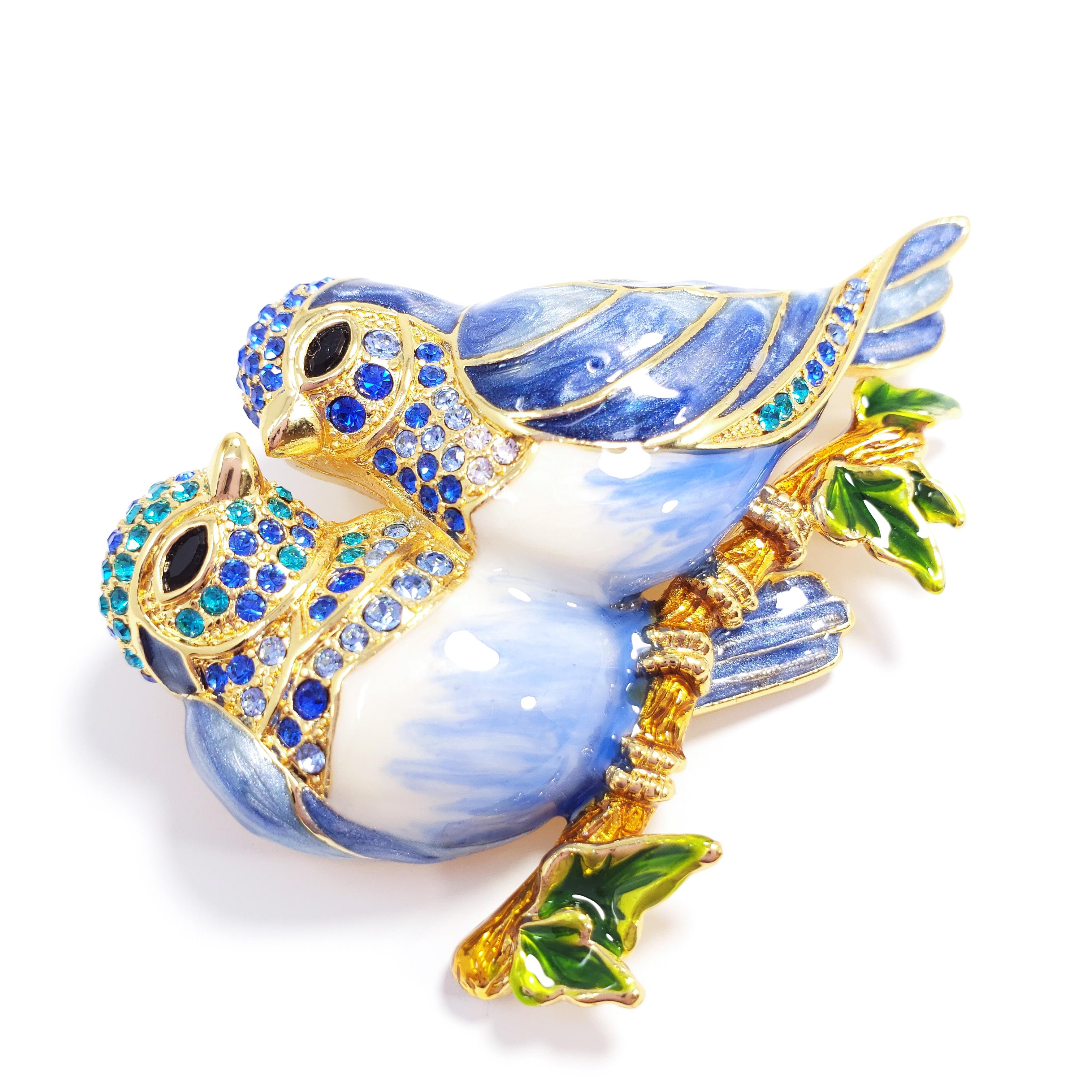 A vibrant pin / brooch / pendant featuring two lovebirds on a branch, painted in blue and white enamel, accented with Swarovski crystals. 

Hallmarks: Jay, Jay Strongwater, CN

By Jay Strongwater, originally for HSN. Sold out everywhere!