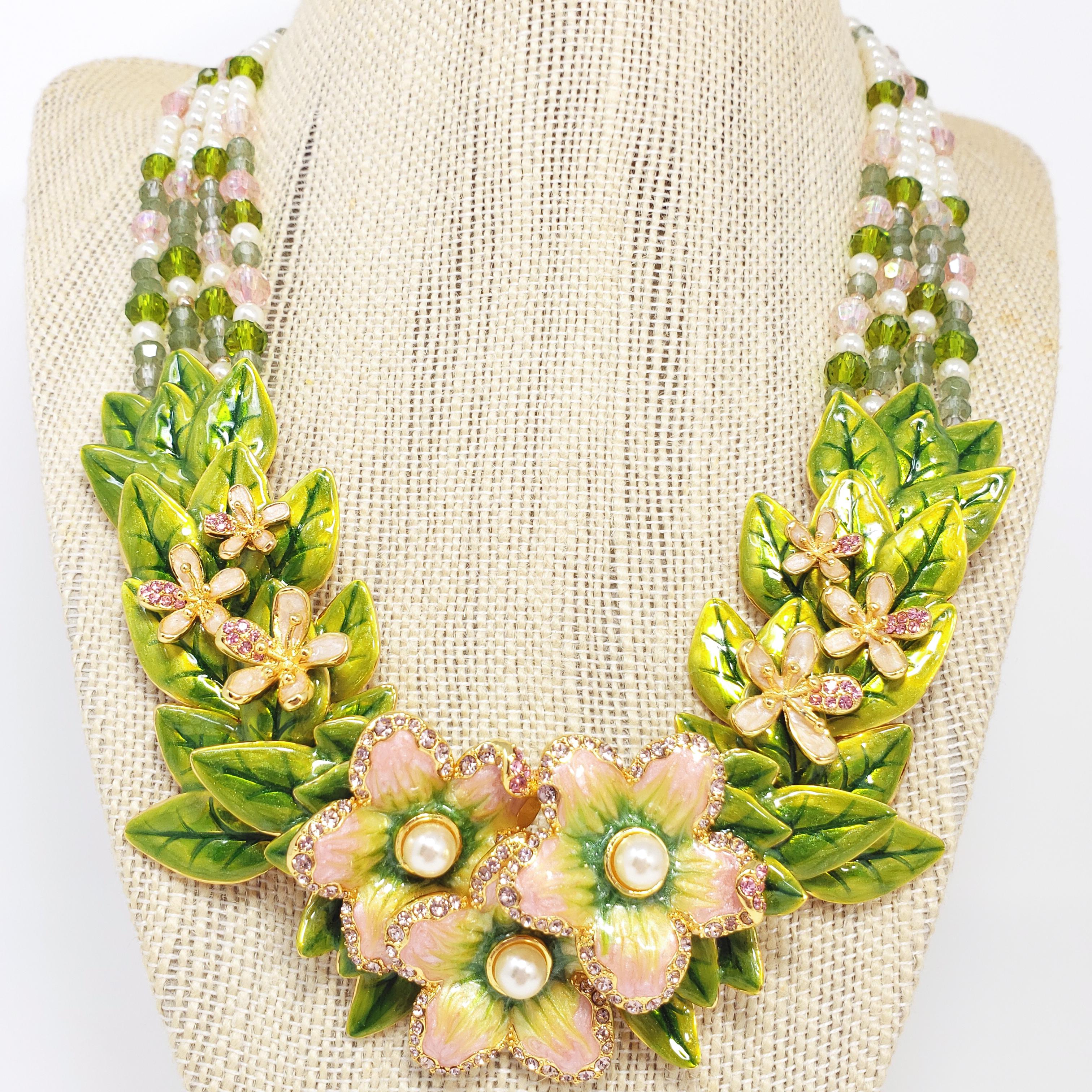 Flower power! An ornate floral necklace featuring green and pink crystals & faux pearls on multiple strands. Layered segments of enameled leaves and flowers accented with crystals and faux pearls sit at the center.

Dimensions: Length 49 cm,