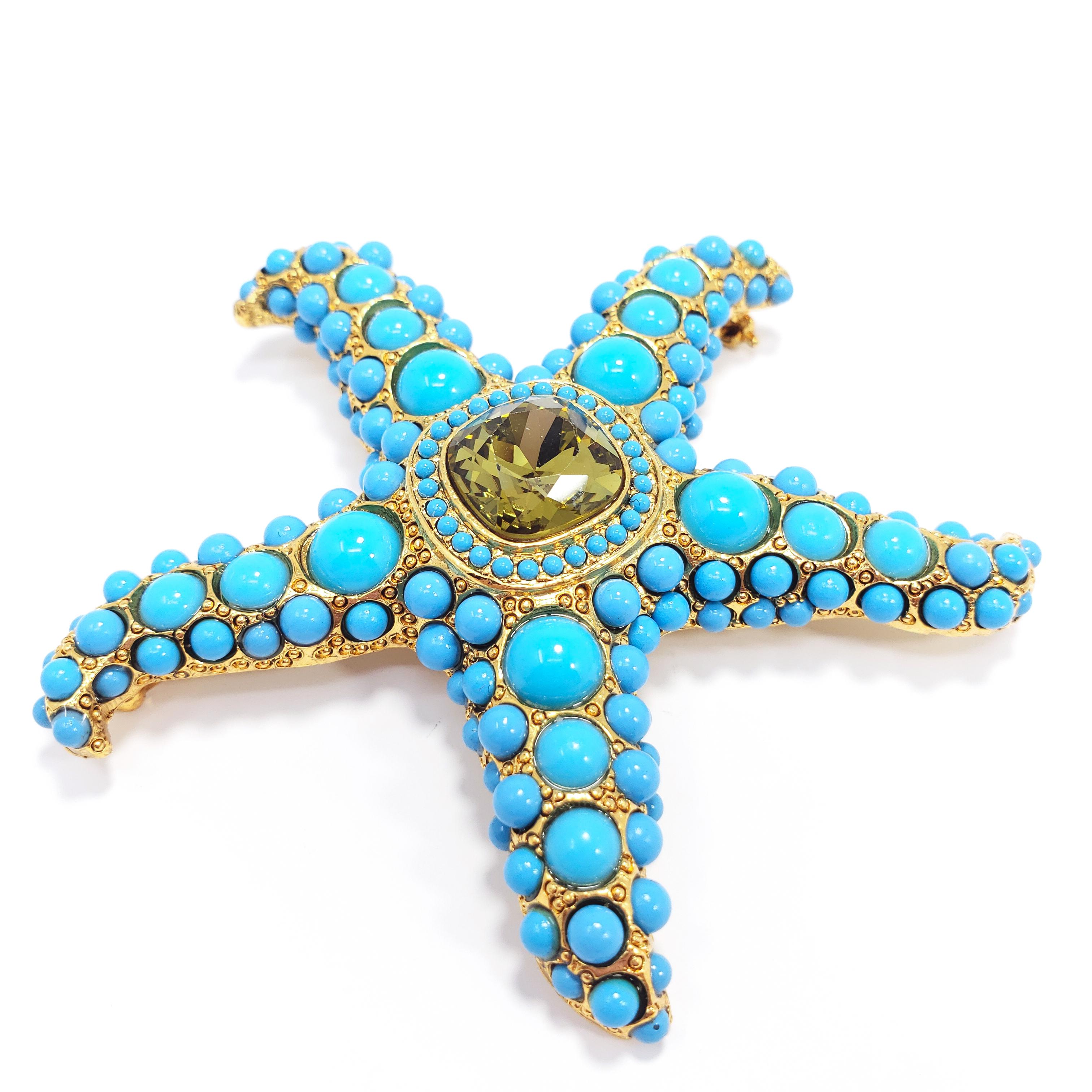 A nautical-themed starfish brooch/pin decorated with pave turquoise cabochons and a centerpiece olive crystal. Gold plated metal setting.

Hallmarks: Kenneth © Lane