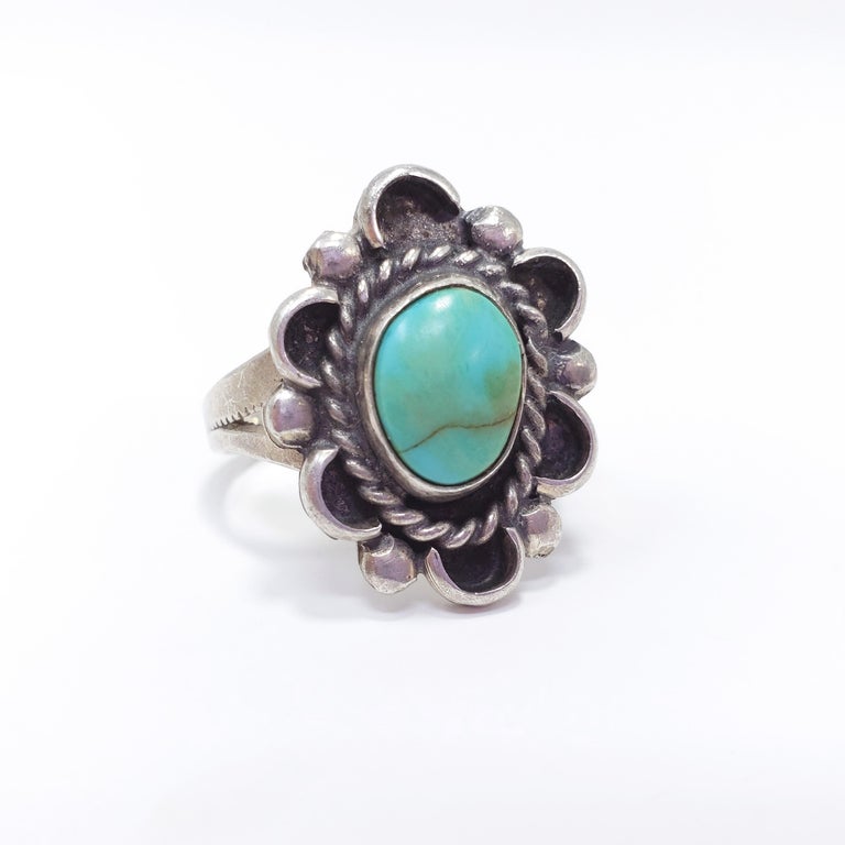 A Native American Navajo ring featuring a genuine turquoise cabochon set in a bezel in a decorative sterling silver base.

Ring size US 8.75
Face dimensions 2.2 x 1.8 cm