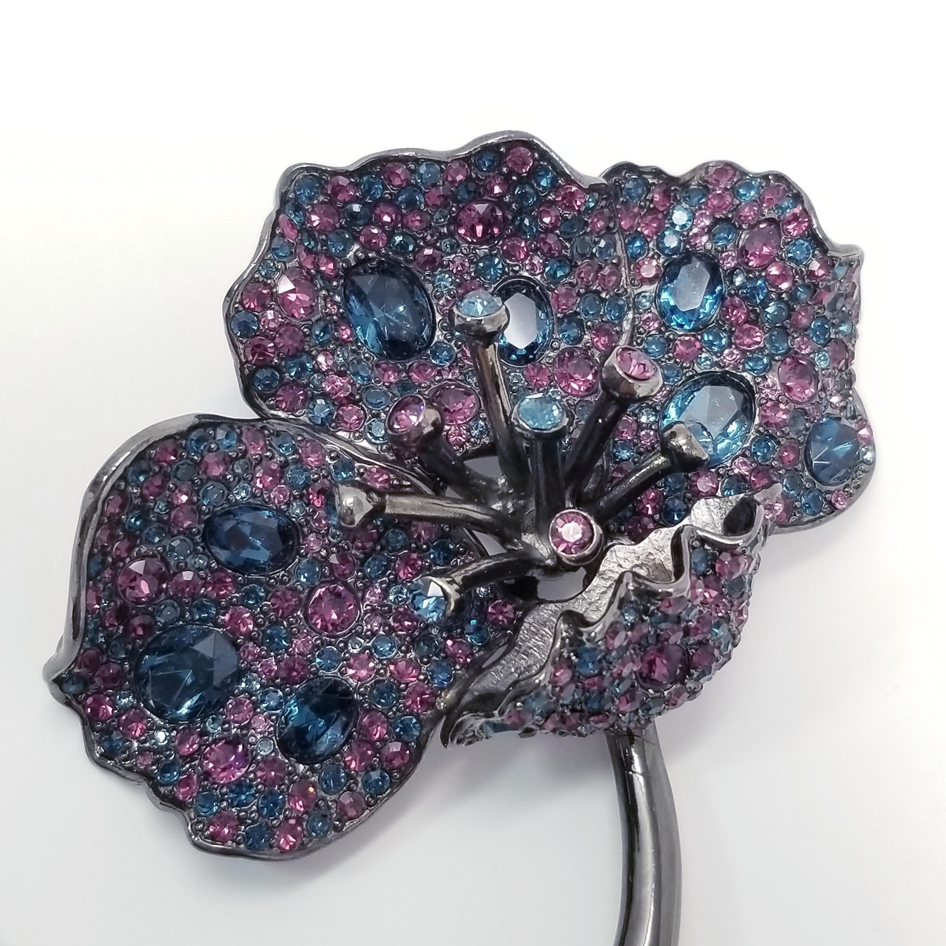 Pave jungle poppy brooch by Kenneth Jay Lane. Exotic cosmic colors! This dark gray gunmetal-tone flower is decorated with faceted sapphire and amethyst colored crystals. 

...

Clasp: Pin stem with safety clasp

Metal Type: Dark gray gunmetal