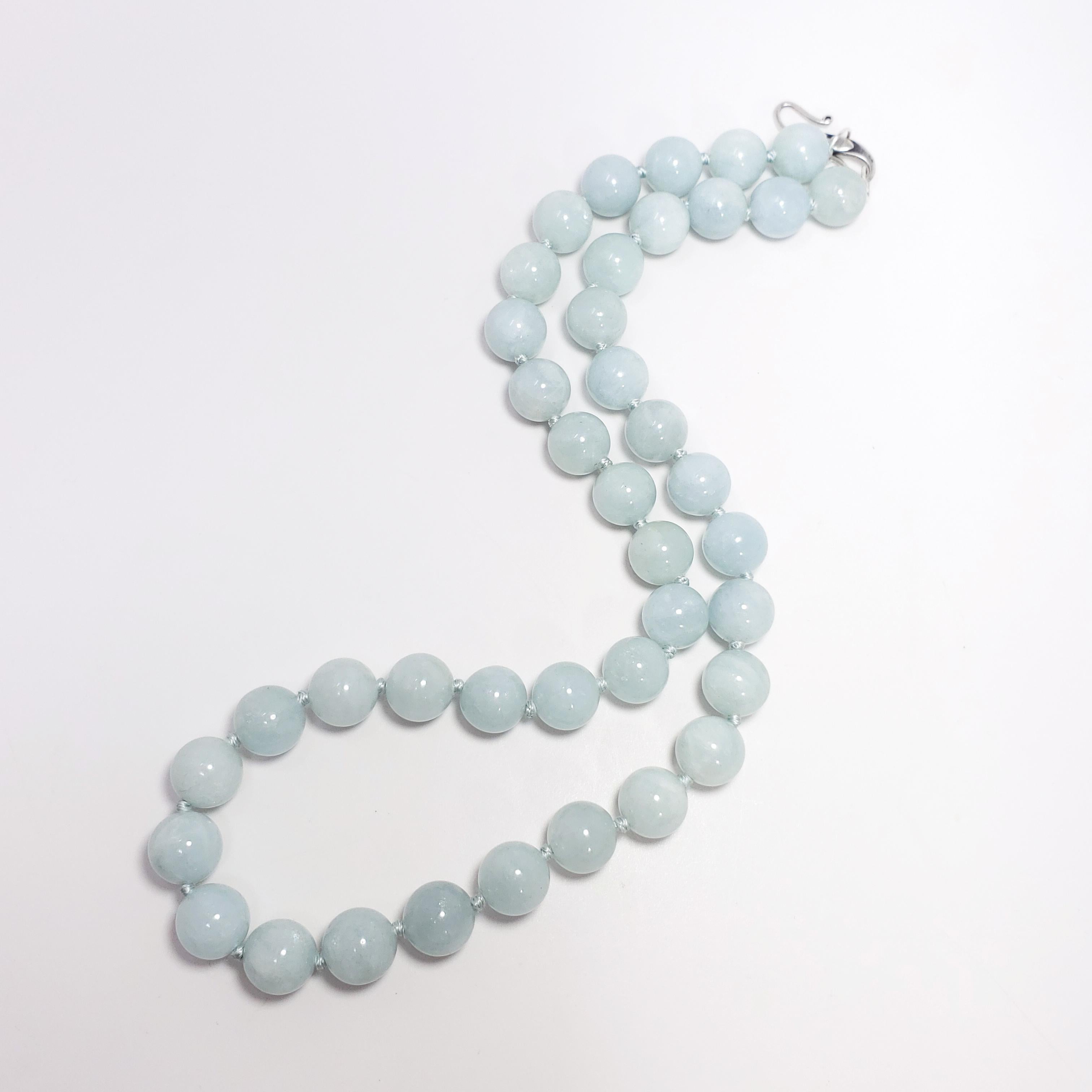 Natural polished aquamarine beads on a teal-colored knotted string, with a matching sterling silver hook and ring clasp. Accentuate your attire with this soft-colored, sophisticated, vintage accessory! 

Beads are approximately 10mm each, and the