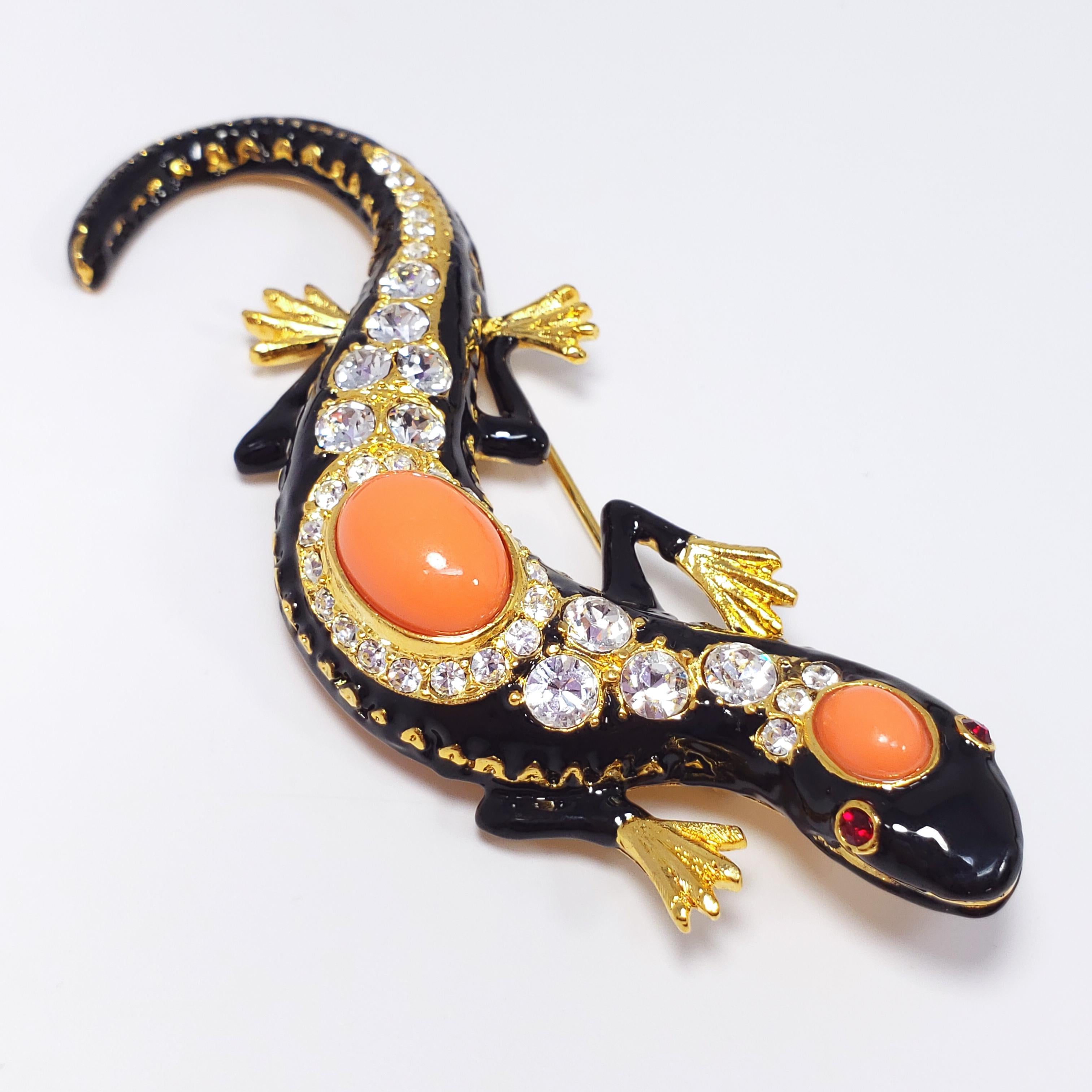 A whimsical salamander/lizard/gecko brooch by Kenneth Jay Lane. Painted black enamel body, adorned with coral-colored cabochons and sparkling clear and red crystals. Set on vibrant 22KT gold plated metal.

Dimensions approx 9.5 x 2 cm. Signed