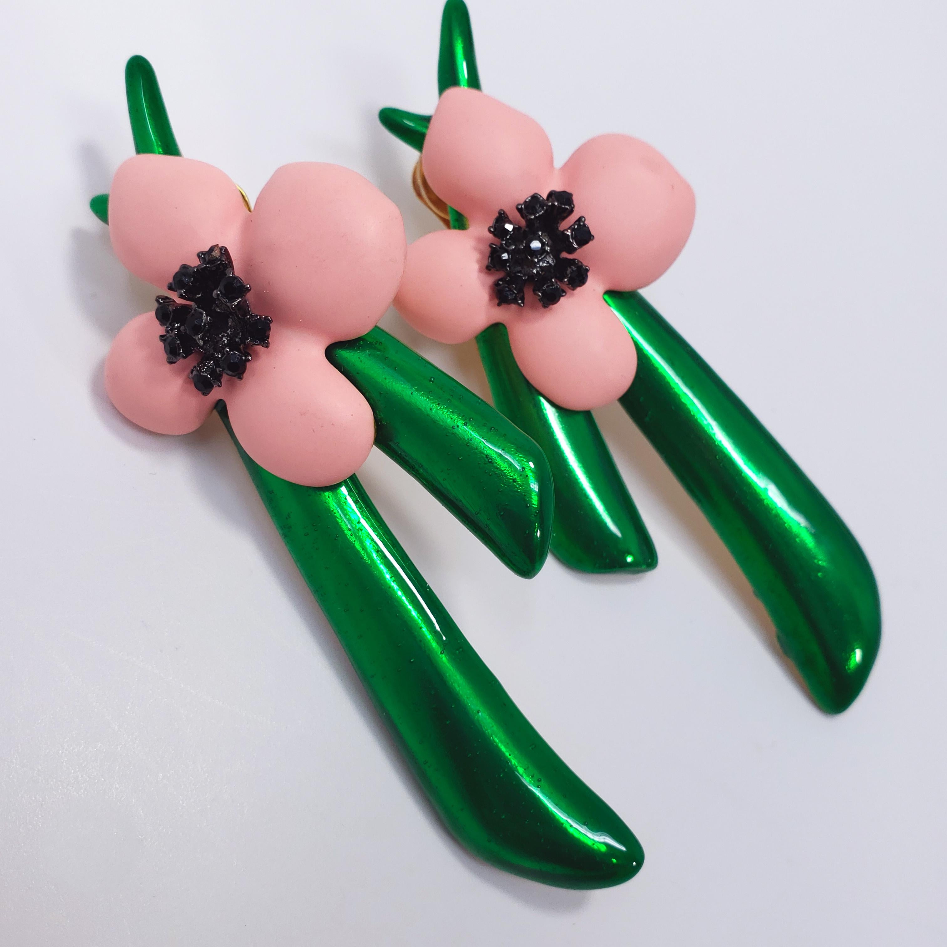 Blooming beauty! A charming set of clip on earrings from a rare Oscar de la Renta floral collection. The flowers feature soft pink resin petals and a painted green stem. The jet black crystals add striking contrast to these bright and colorful