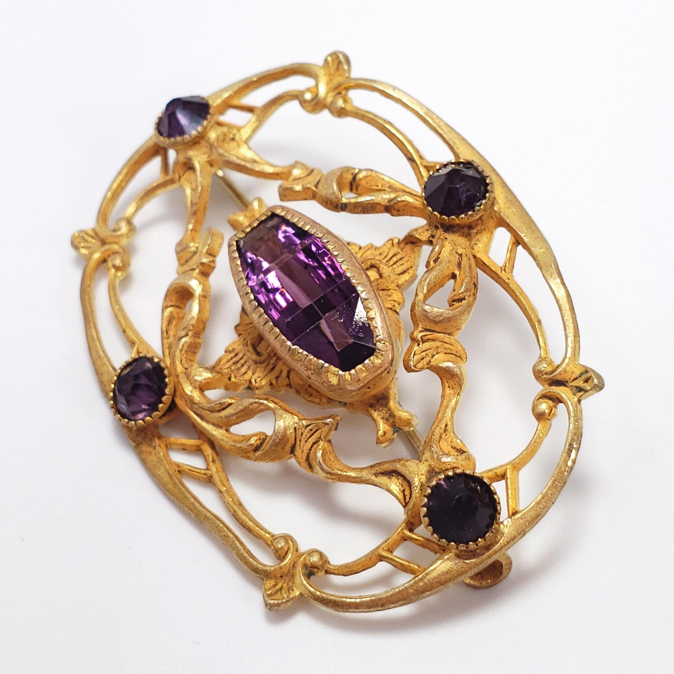 A centerpiece open-back amethyst in a unique cut, set in an ornate vermeil frame, typical of the time period. Accented by 4 smaller chaton crystals on all four sides. Fastened with antique hook clasp.

Hallmarks: A maltese cross motif on the pin C