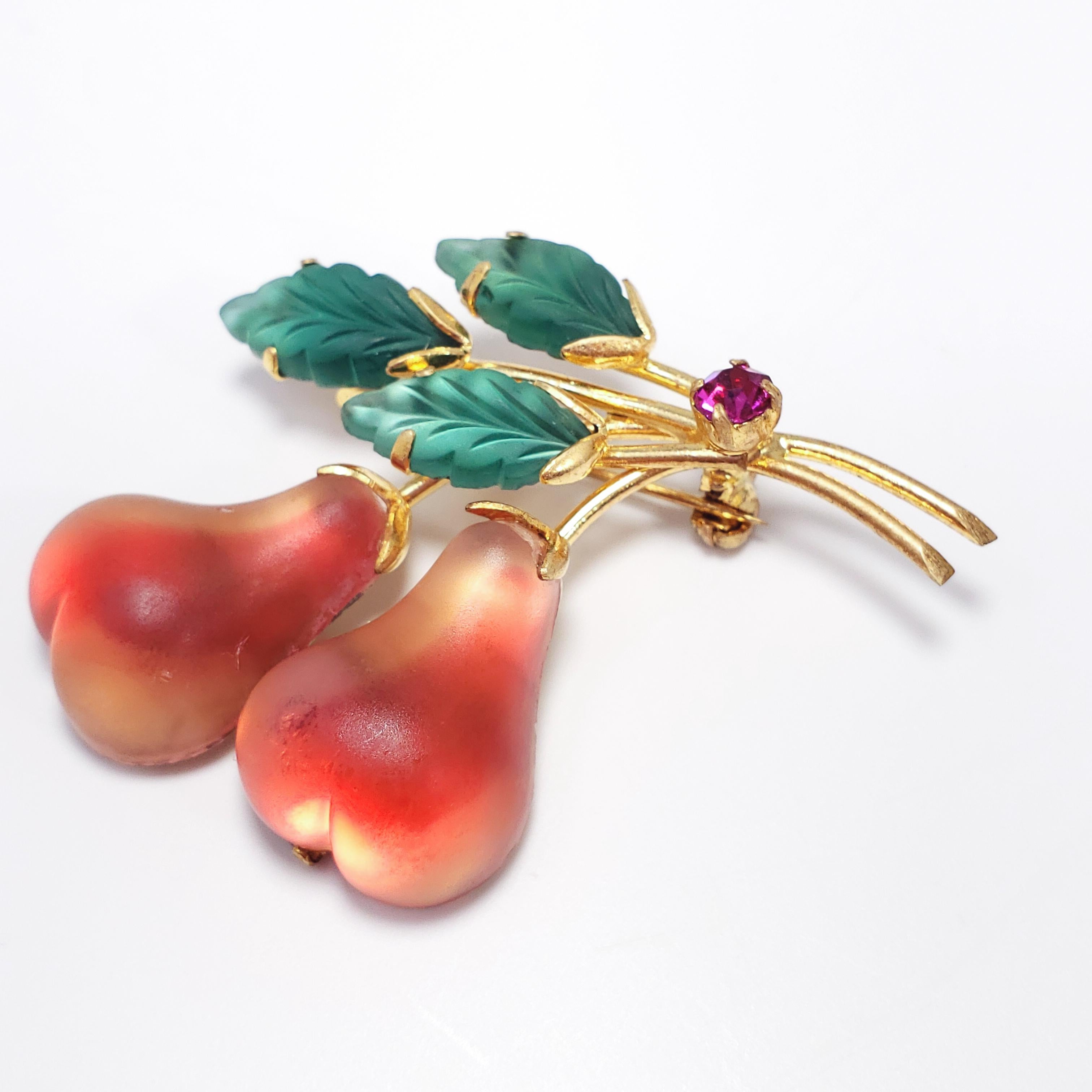 This lovely pin features two multi-color glass pears and three green glass leaves, all prong set and accented with a single violet crystal. Set in gold-tone metal. A vintage accessory perfect for lovers of Austrian jewelry!

Hallmarked