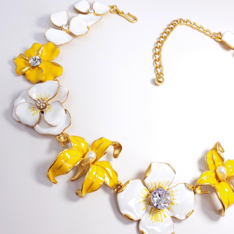 This textured 22K gold-plated metal features an assortment of linked white and yellow enameled flowers, accented with crystals and faux pearls. By Kenneth Jay Lane, made in USA.

Weight: 119 g
Hallmarks: Kenneth © Lane
Flower sizes from 2.6 to 4.1