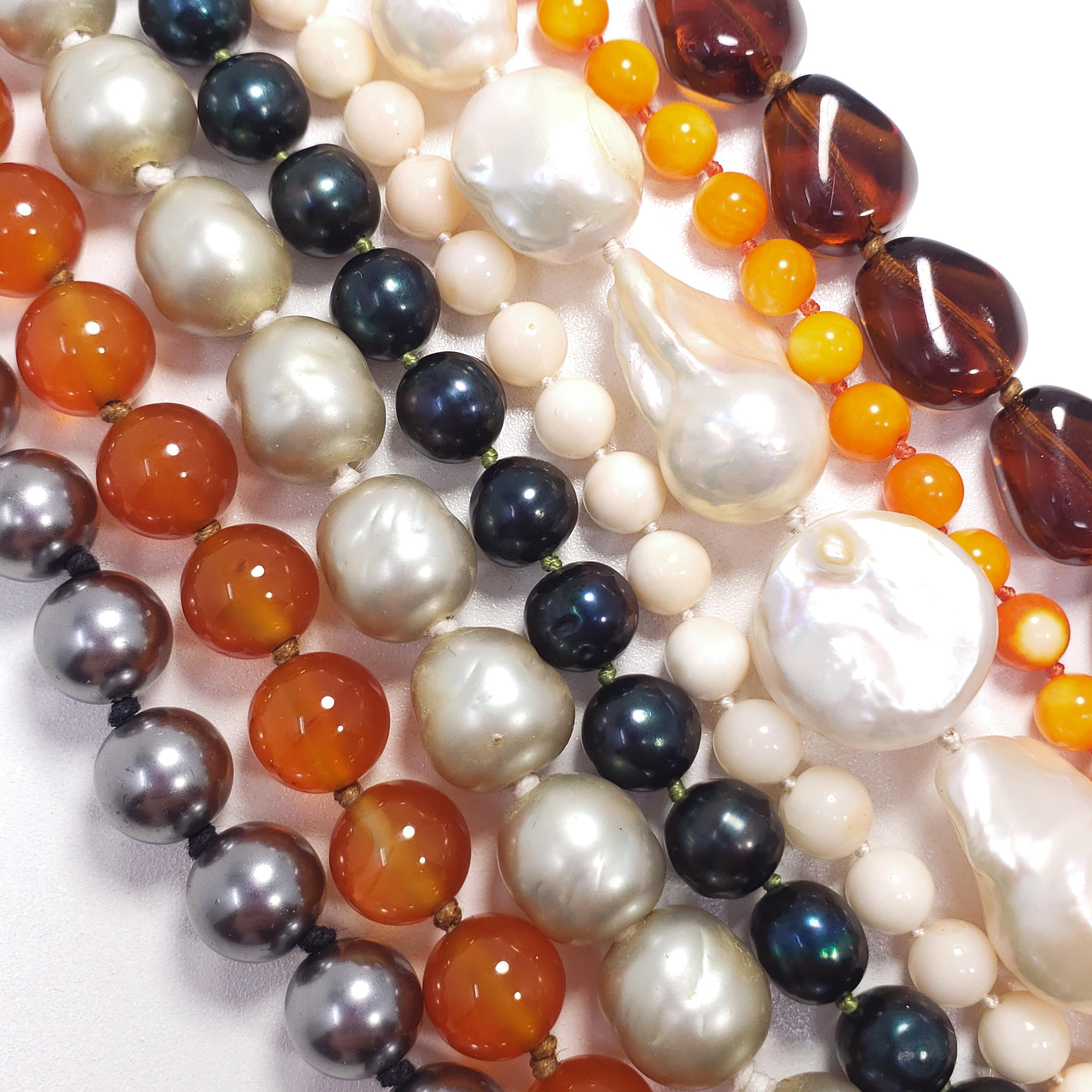 A multi-strand, knotted-string, beaded necklace. Features an assortment of genuine and faux beads that all come together into a sophisticated, twisted-strand art piece! Features a faux pearl box clasp set in a gold plated bezel, hallmarked