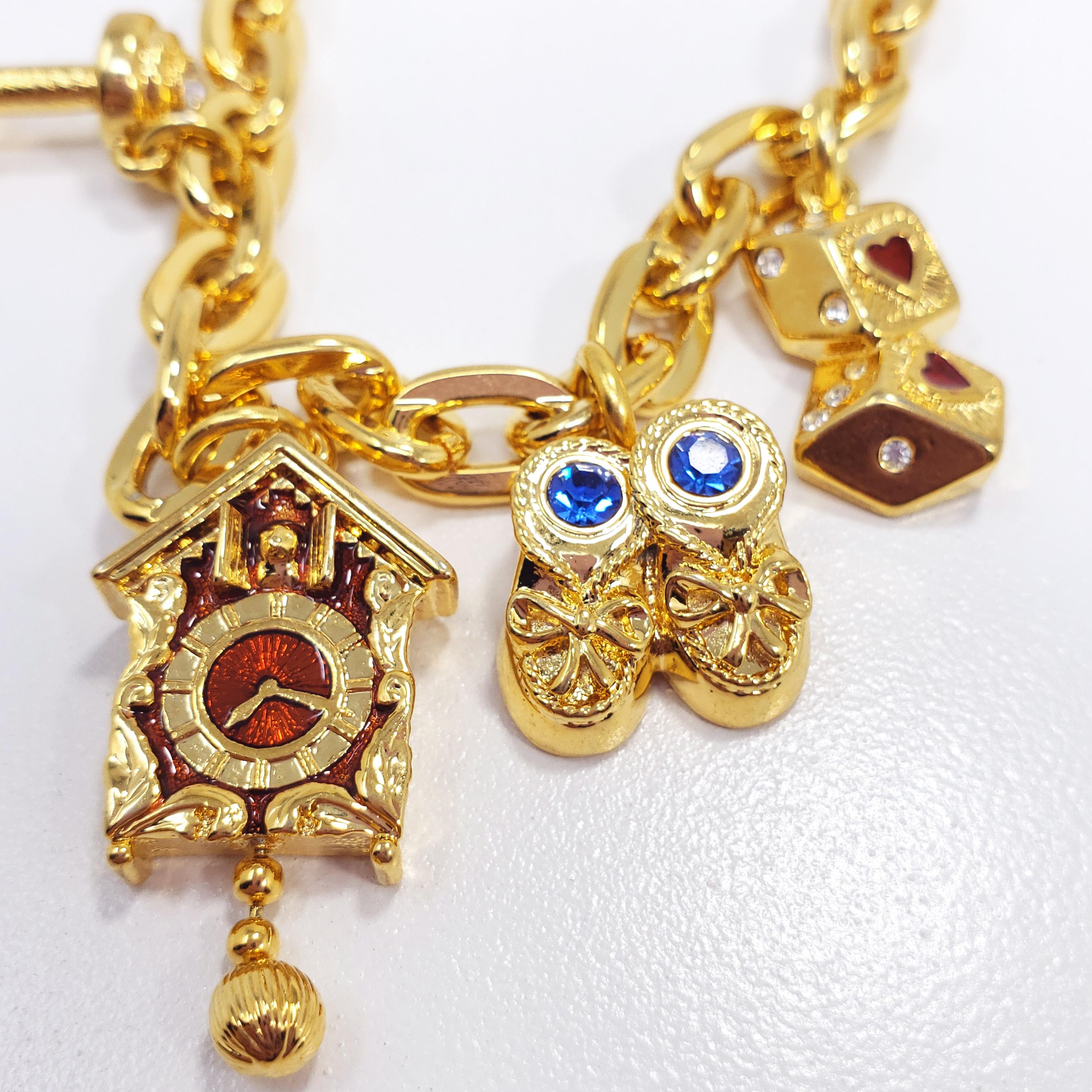 A gold-plated chain bracelet with five charms - a pair of lucky dice, shoes, a cuckoo clock, a dumbbell, and MO' $ motif. Accented with crystals and enamel, fastened with a toggle clasp. By Kenneth Jay Lane

Hallmarks: © KJL