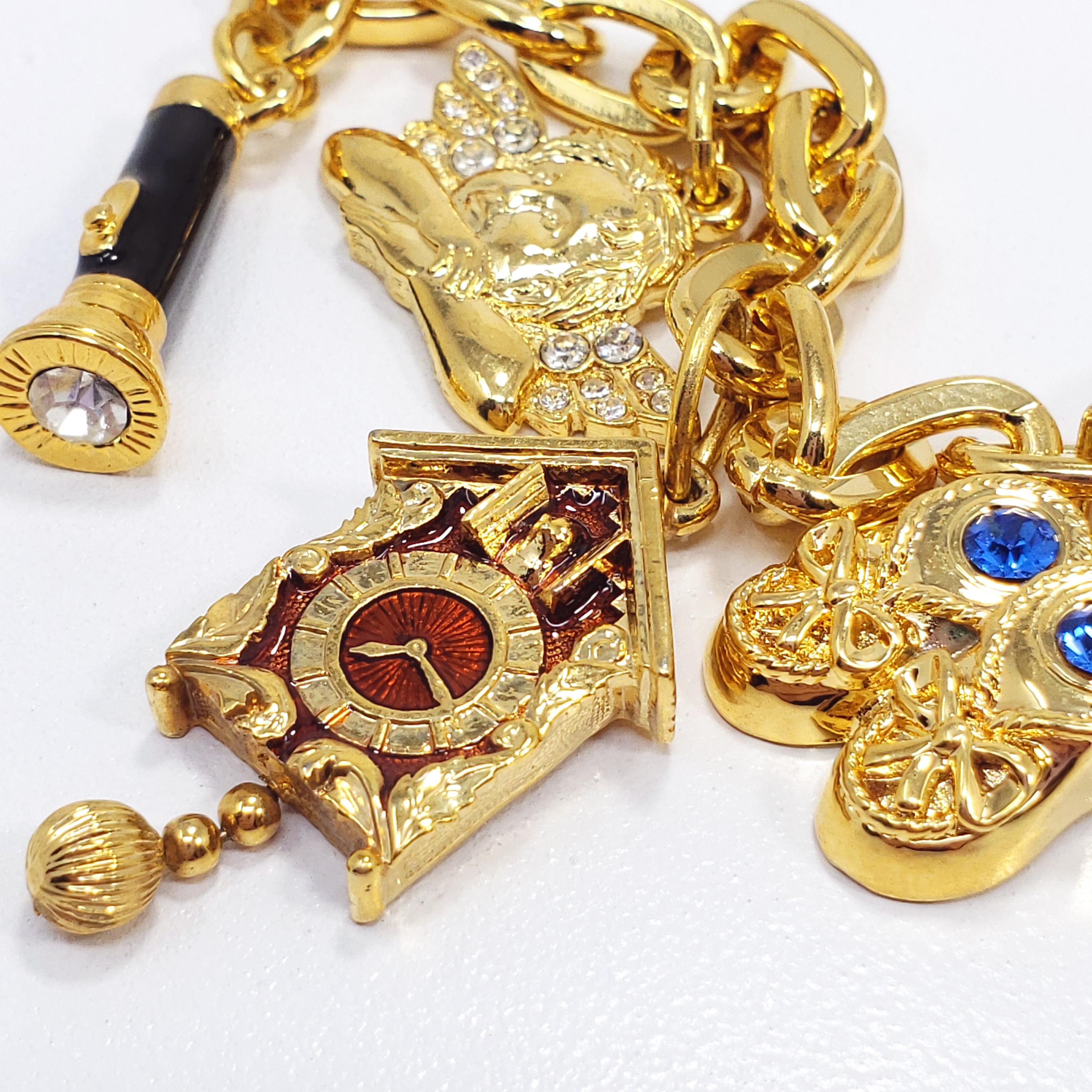 A gold-plated chain bracelet with five charms - a pair of lucky dice, shoes, a cuckoo clock, an angel, and flashlight. Accented with crystals and enamel, fastened with a toggle clasp. By Kenneth Jay Lane.

Hallmarks: © KJL