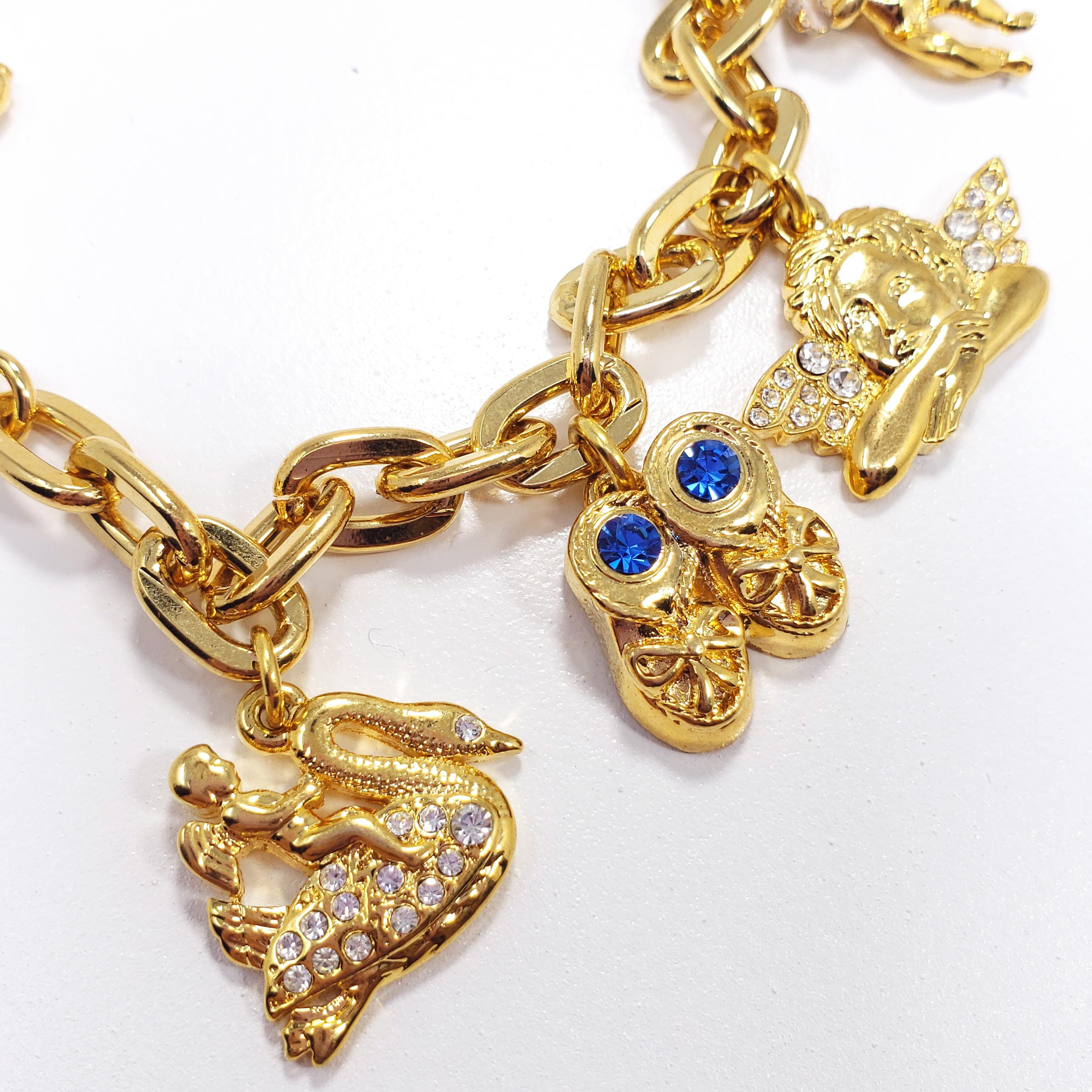 A gold-plated chain bracelet with five charms - a pair of lucky dice, cherub, an angel, a pair of shoes, and a swan. Accented with crystals and enamel, fastened with a toggle clasp. By Kenneth Jay Lane.

Hallmarks: © KJL