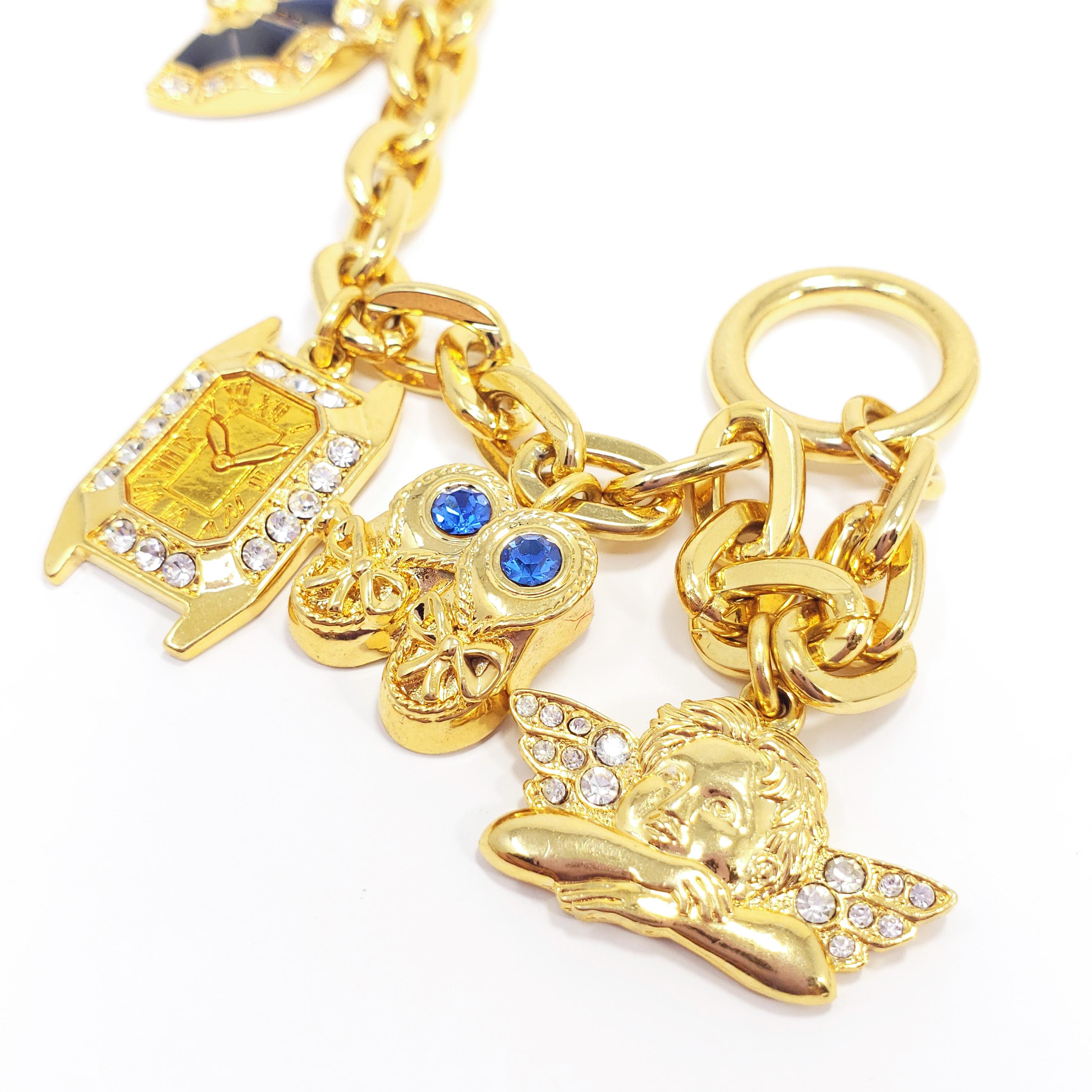 A gold-plated chain bracelet with five charms - a ladybug, a hand fan, a clock, a pair of shoes, and an angel. Accented with crystals and enamel, fastened with a toggle clasp. By Kenneth Jay Lane.

Hallmarks: © KJL