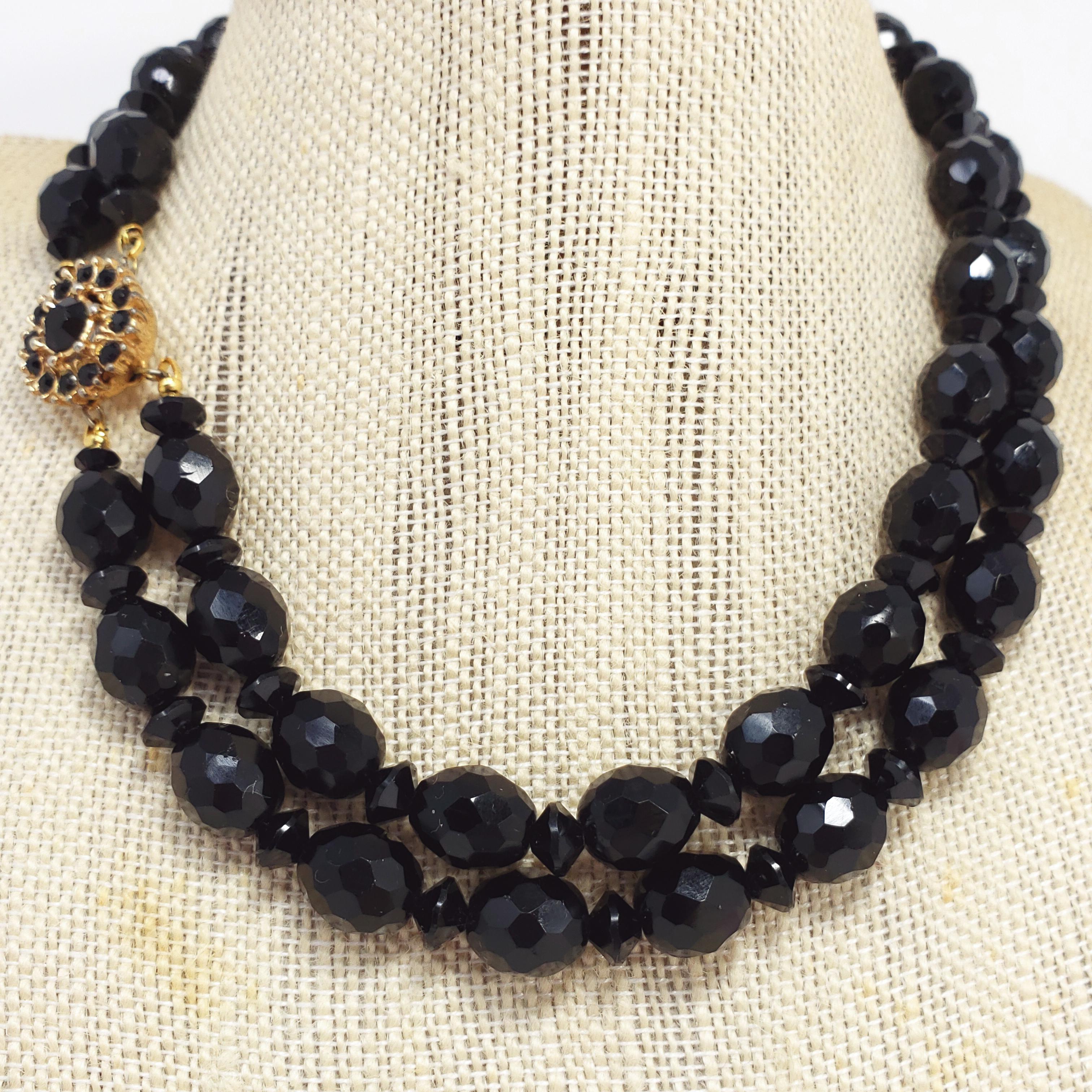 A double strand necklace featuring alternating-sized black faceted jet beads, accented with a jet-encrusted gold-plated box clasp. Circa 1960s.

Hallmarks: bergere