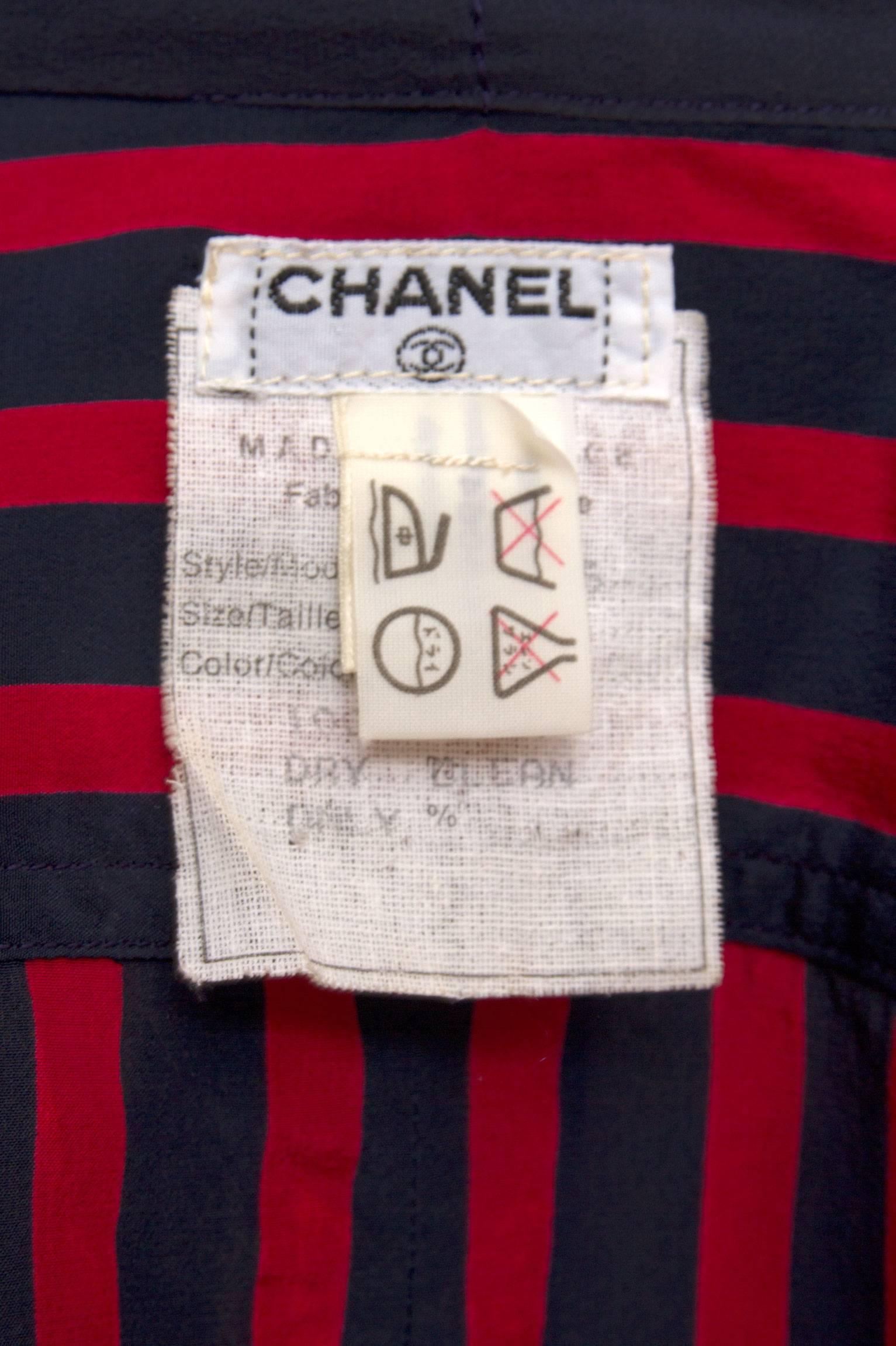A cute 1980s Chanel short sleeved silk blouse with a front buttoned closure and vertical stripes in navy and red. The blouse has a large tie neckline which can be tied into a voluminous pussy bow and navy turn up sleeves that are held in place by a