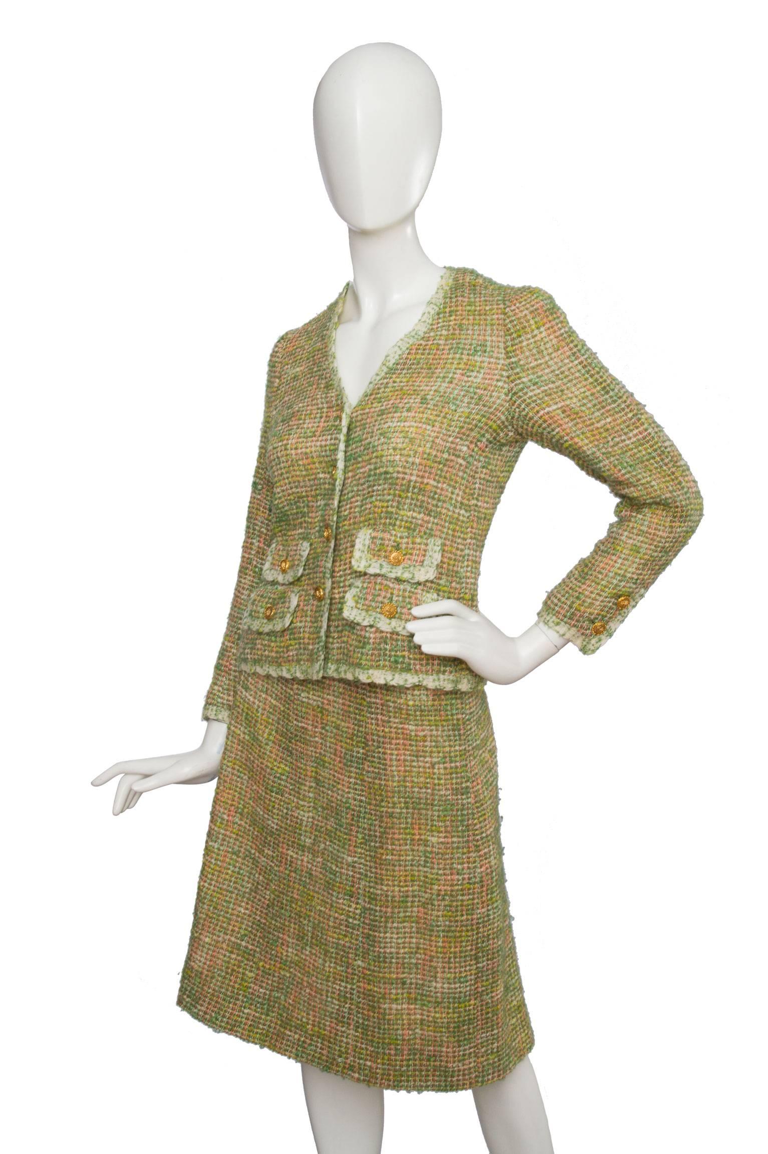 A light green 1960s Chanel haute couture  skirt suit with light pink accents consisting of an a-line skirt and a fitted front buttoned jacket. The jacket has a deep v-neckline and four mock flap pockets on the front. The skirt has a back zipper and