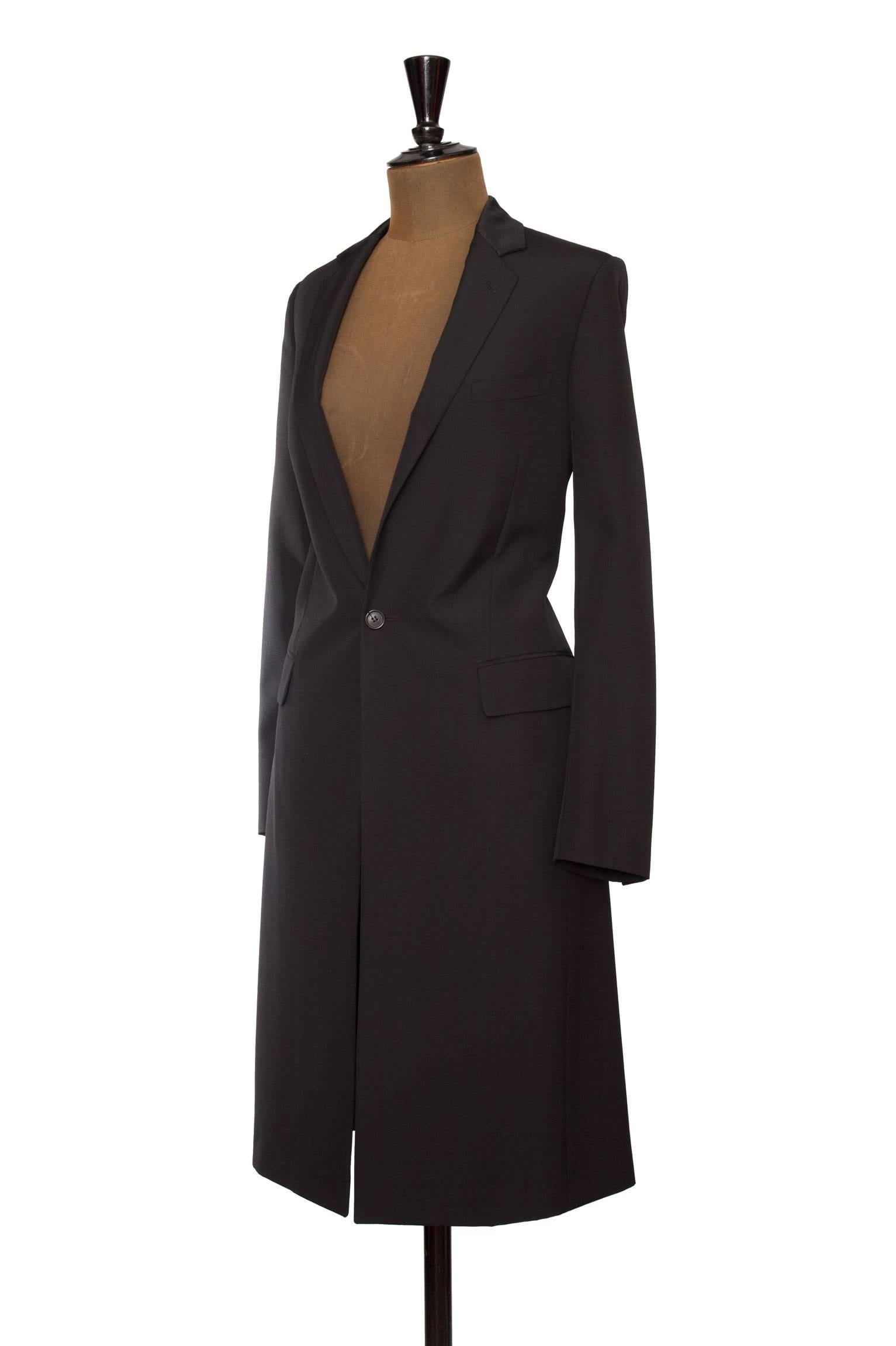 A tailored 90s black Christian Dior jacket with a flap welt pocket situated on each side of the hip, slim lapels and a single front button closure pinch in the waistline in the centre front. The coat is fully lined and has structured shoulders.