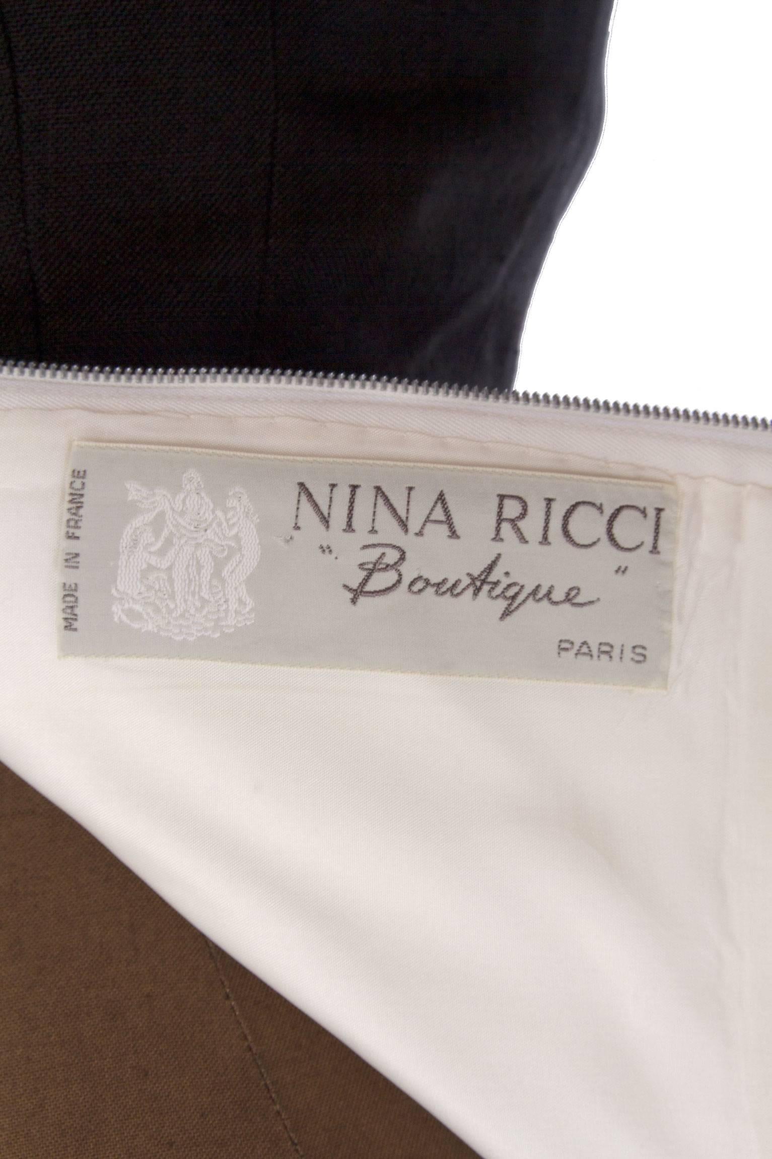 A classic 1980s Nina Ricci linen cocktail dress with a black fitted pencil skirt and an off-white strapless bustier top. The simple yet elegant dress has a beautiful abstract cutout at the top of the dress, which gently frames and covers the
