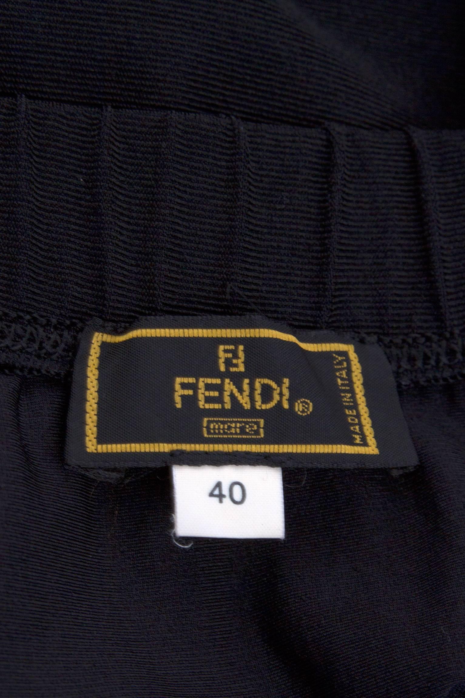 A great 1990s black Fendi two-piece ensemble consisting of a cropped t-shirt and a wrap mini skirt. The top has elasticated ‘Fendi’ trim wrapped around the sleeves and at the waistline, as goes for the elasticated waist of the skirt, which wrap