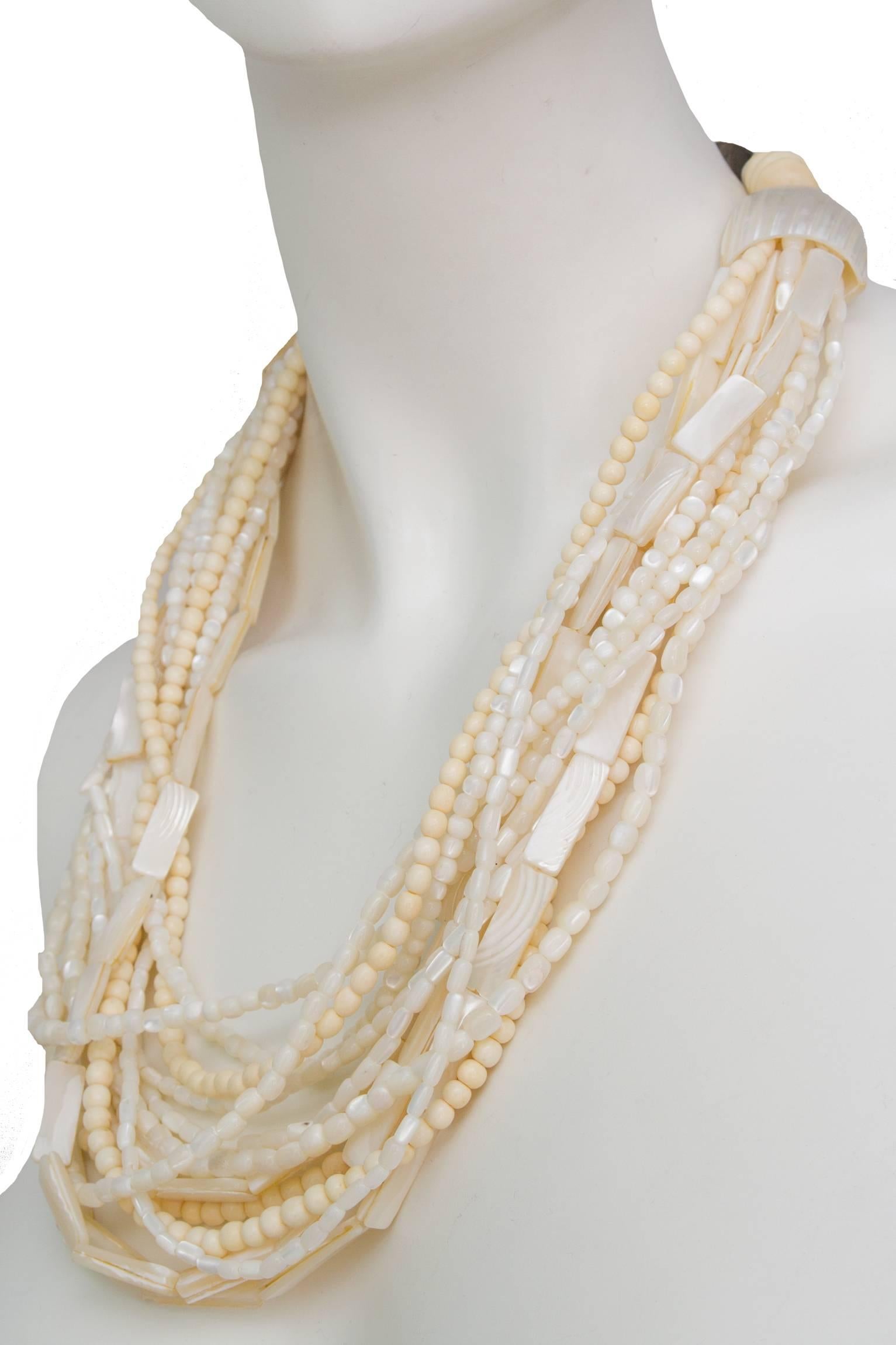 A 1980s Gerda Lyngaard for Monies mother-of-pearl beaded necklace with multiple strands of beads in varying shapes and sizes. The strands are gathered at the back in a large mother-of-pearl shell and fastened by beads to a large s-shaped closure.