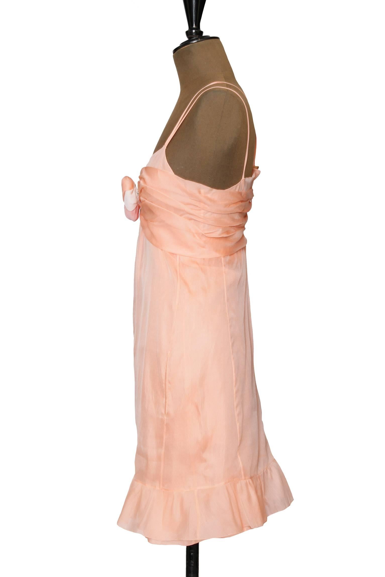 A delicate 1990s Chanel light pink negligee with a sheer overdress, a ruffle hemline and a ruched trim across the bust. In the center front, the dress has a detachable white & pink rose applique fastened with a safety pin. The dress is held up