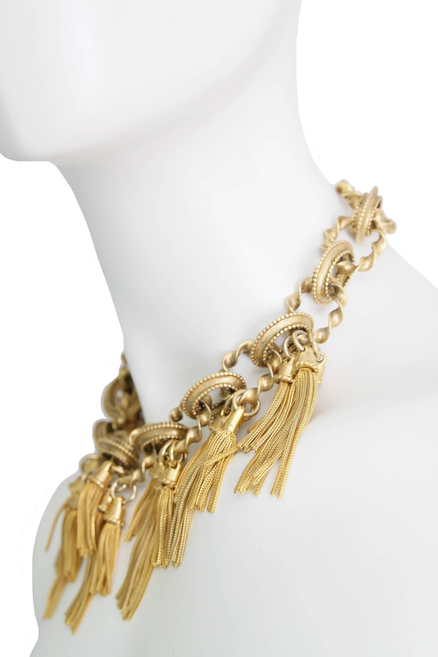 A 1980s gold toned Karl Lagerfeld oversize chain link necklace with large gold-toned tassel embellishment hanging from every other link in the center front. The tassels hang in clusters of three with each middle one being slightly longer. The