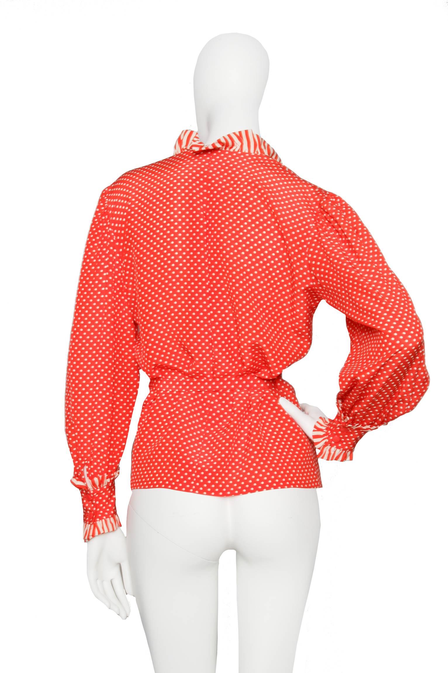 A bright red 1980s Christian Dior white polka dot wrap blouse with long sleeves and a contrasting candy striped trim around the neckline and cuffs.The blouse has two buttoned cuffs and closes in the side with a long tie belt. 

The size of the