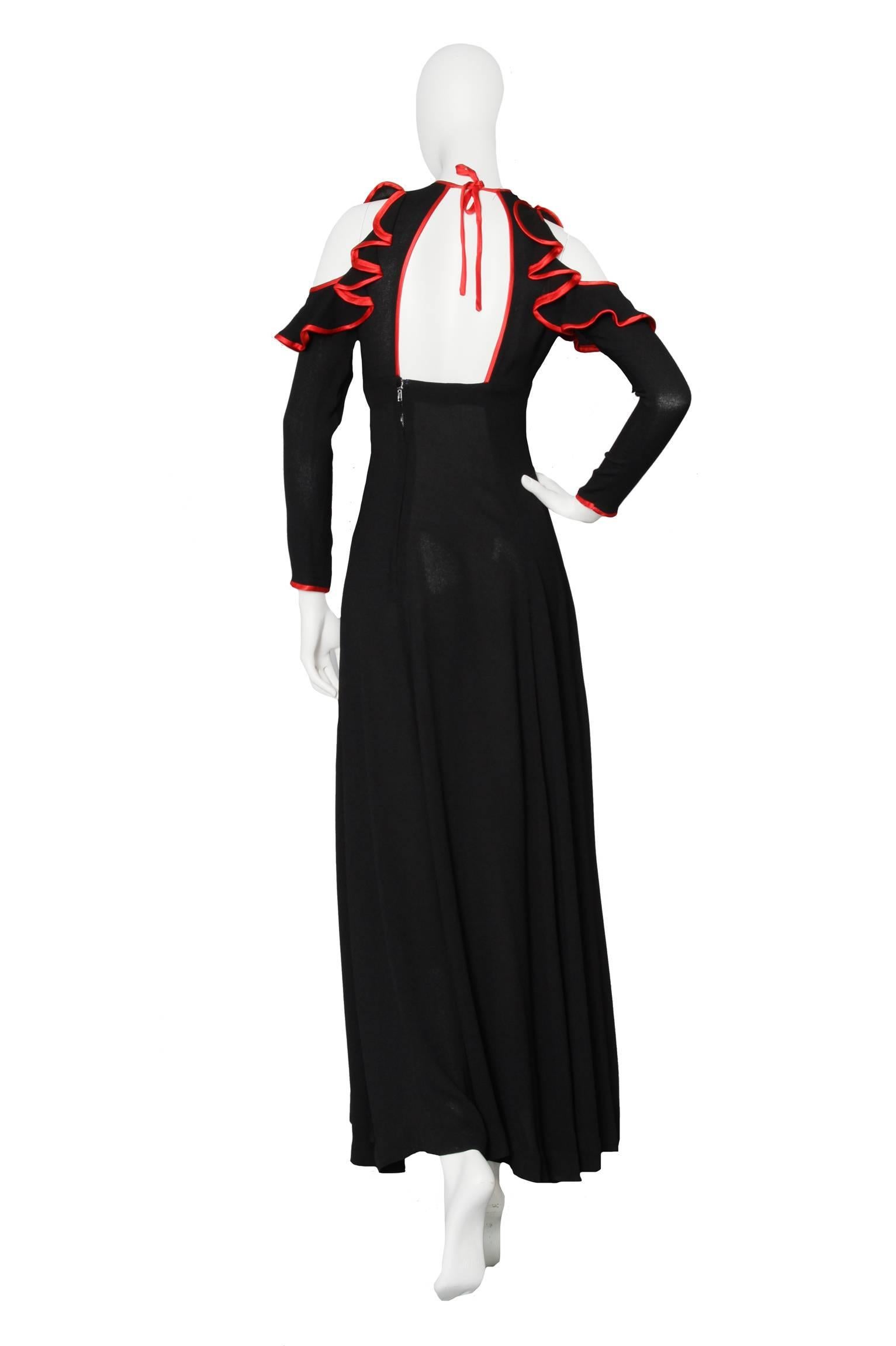 An absolutely stunning 1970s black Ossie Clark ankle-length moss crepe dress with long tapered sleeves and cut-out shoulders. The dress has a fitted waistline and a key-hole cut-out in the front, with contrasting red piping. The red silk is repeated
