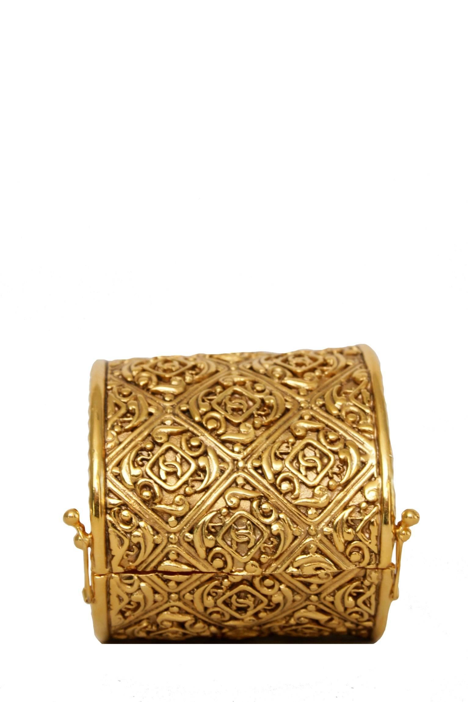 An extravagant 1980s gold-toned Chanel Cuff with intricate engravings set in a lattice grid. The engravings are completed with small Chanel double 'CC' logos. The wide cuff is fastened by a safety clasp on both sides.

The cuff is stamped: Chanel,